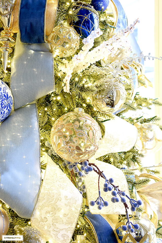 Elegant gold and blue Christmas ornaments and ribbon on a gorgeous faux Christmas tree with LED lights.