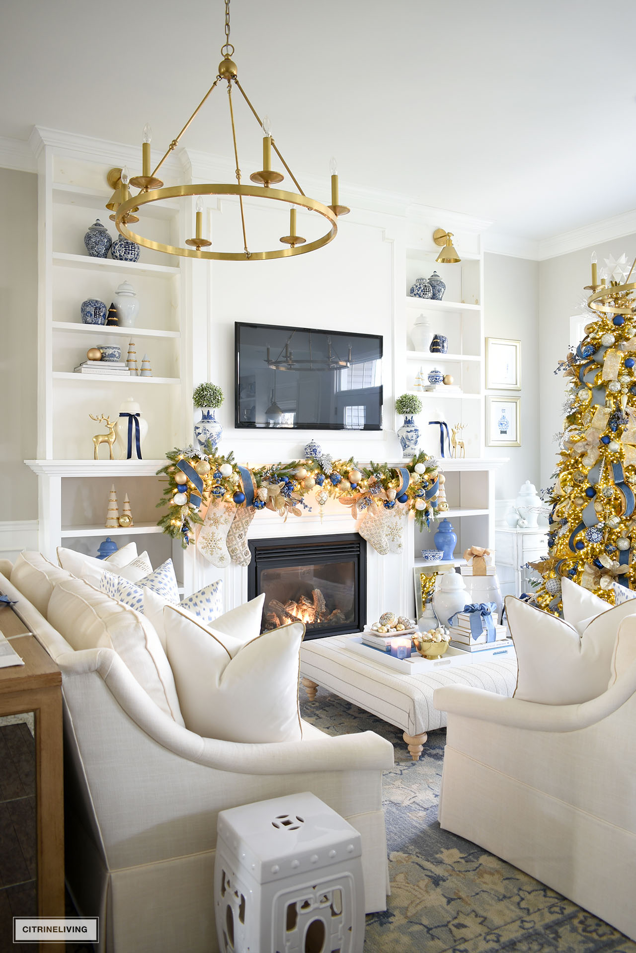 Living room decorated for christmas with white sofas, blue, white and gold holiday decor.