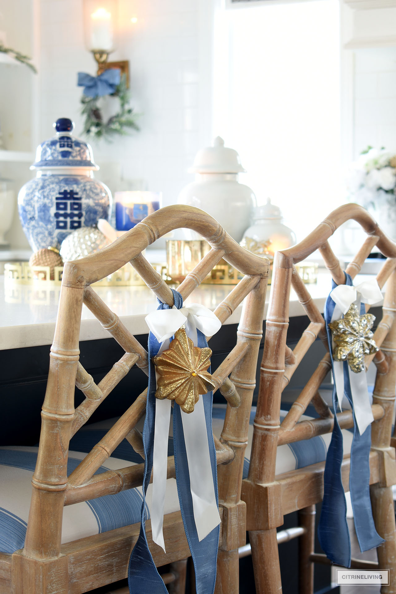 Chinese Chippendale barstools with blue and white striped fabric seats are decorated for Christmas with blue and white ribbon and hanging ornaments.
