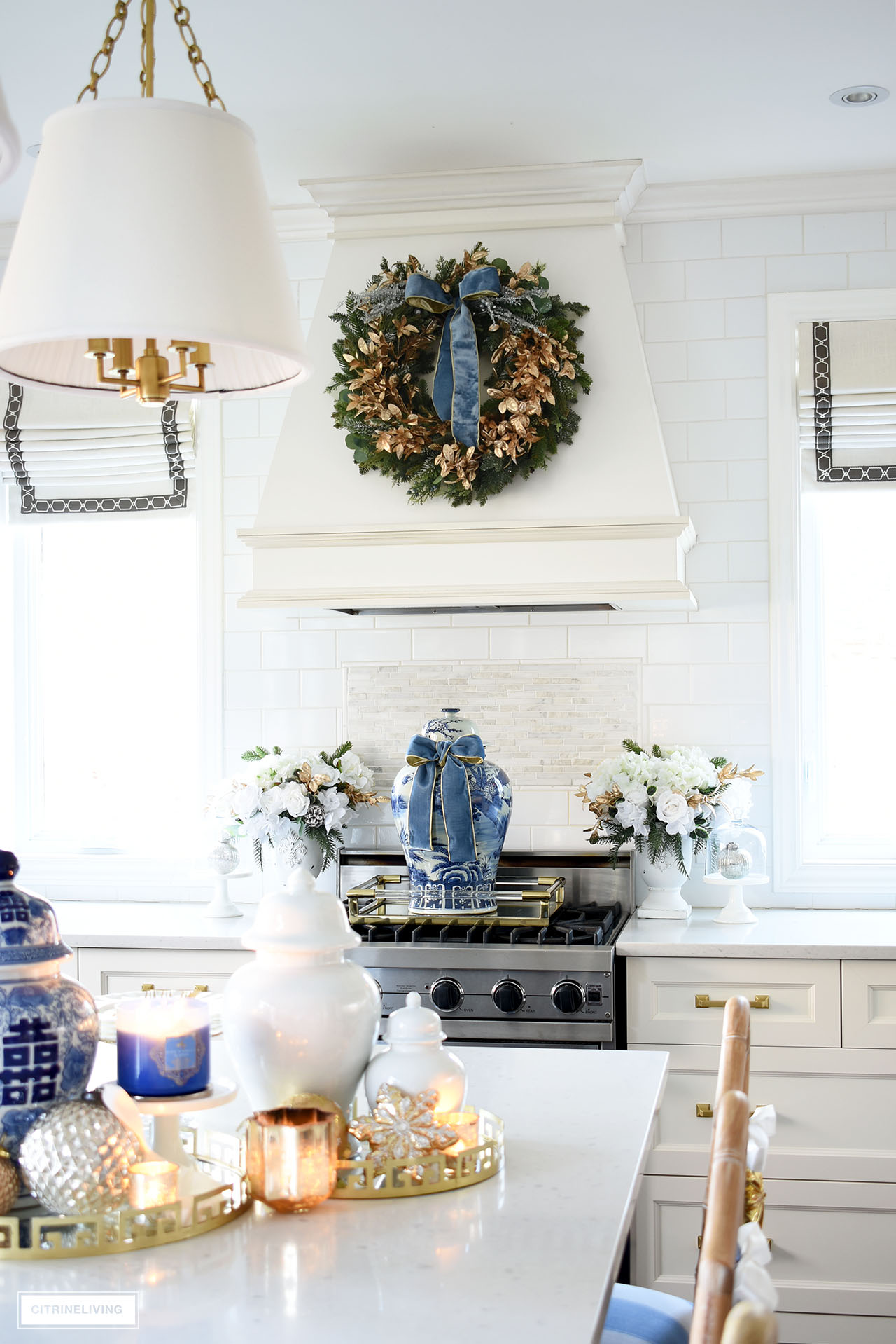 Kitchen range decorated for Christmas with a large blue and white ginger jar tied with blue velvet ribbon, flanked with white, green and gold floral arrangements.