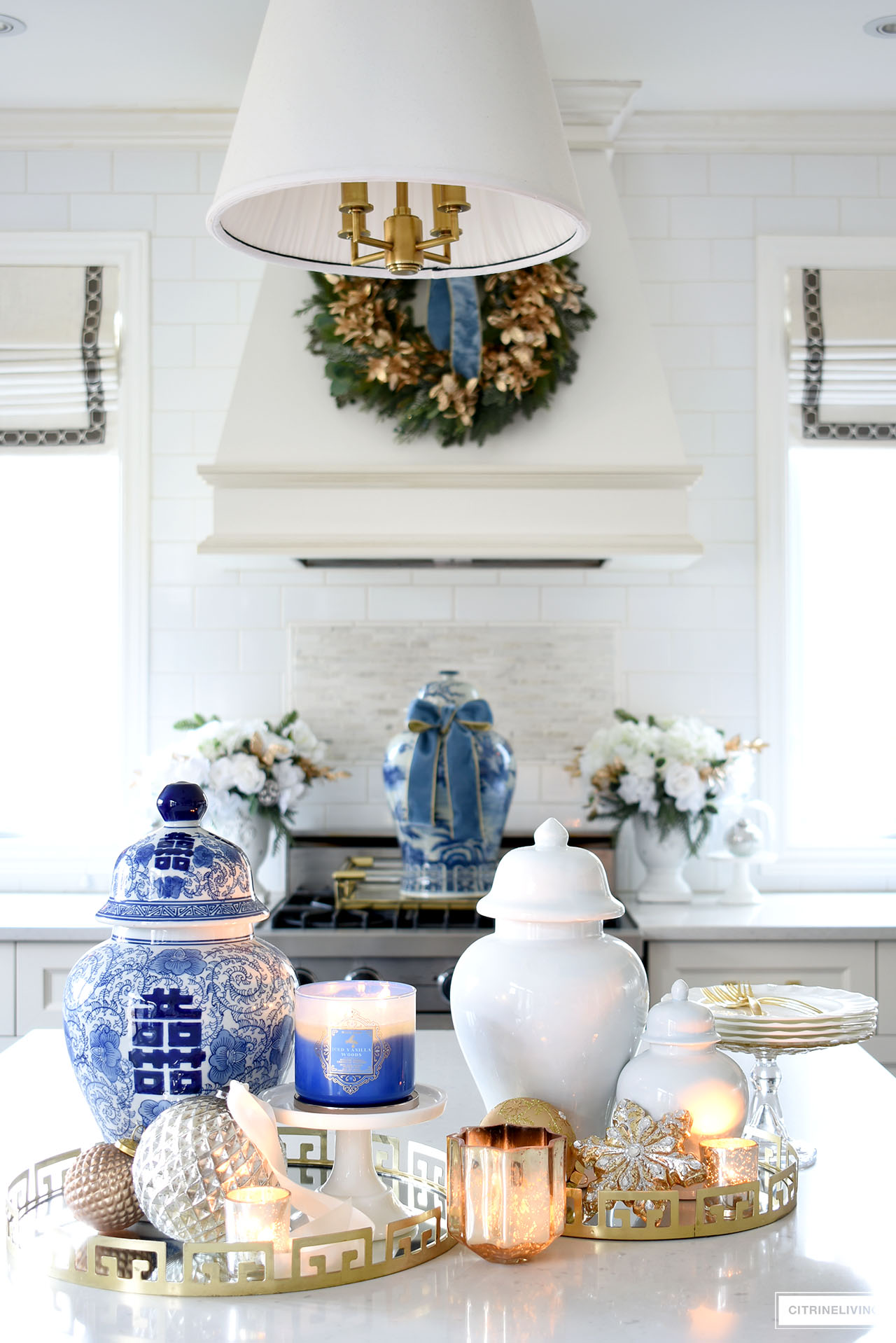 Kitchen island styled for Christmas with ginger jars, candles, ornaments and dishes on beautiful gold trays.