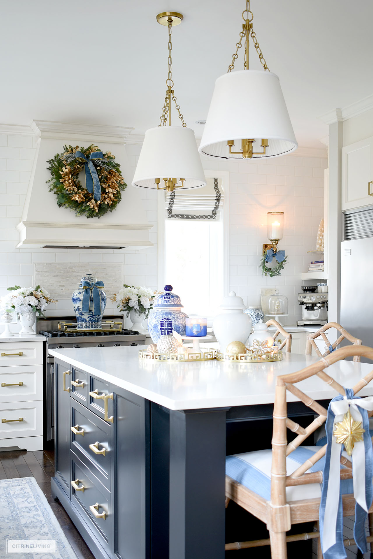 Black kitchen island with gold hardware styled for Christmas with gold trays, candles and ginger jars.