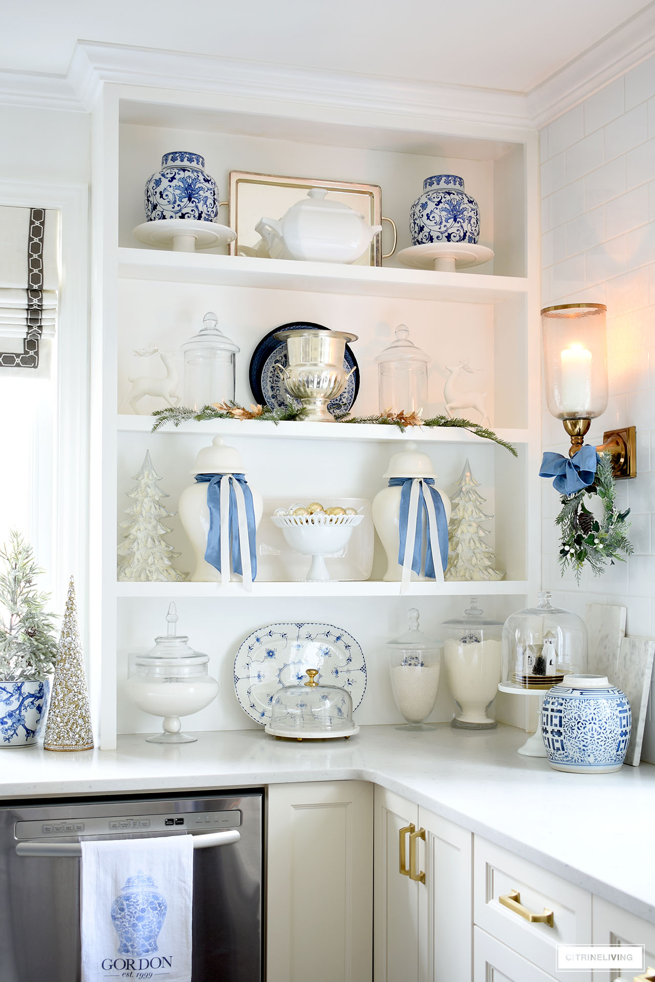 Pretty Christmas decorated kitchen shelves with blue and white touches, greenery and gold accents.