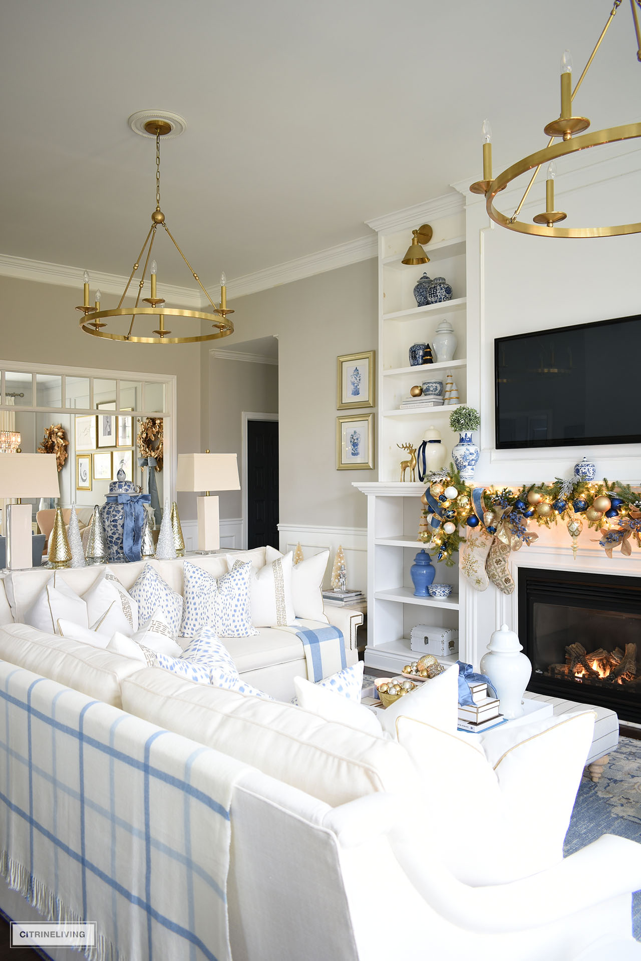 Living room with white sofas, decorated with chic white, gold and blue pillows for Chrsimtas. 