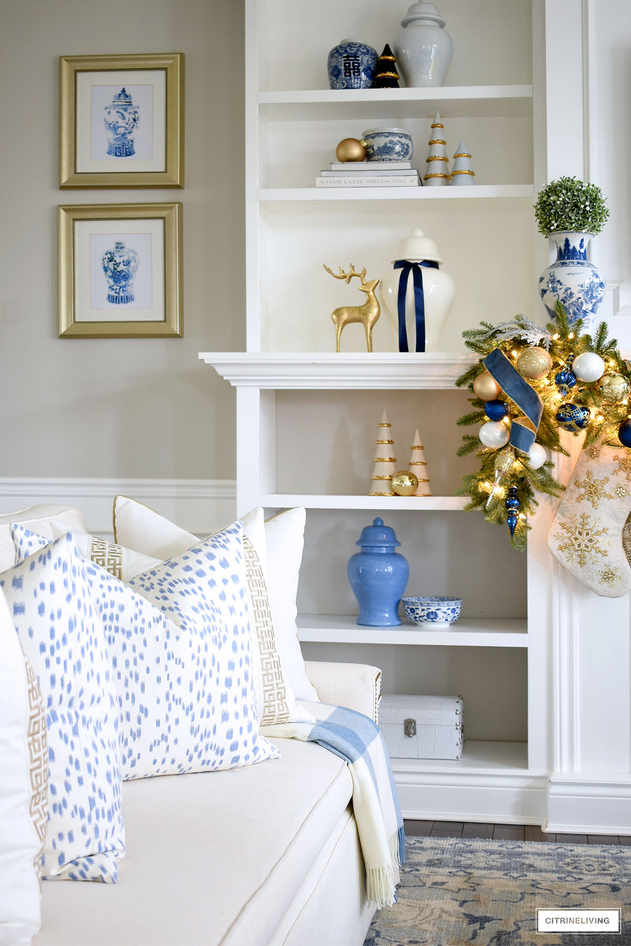 Living room shelves styled for christmas with blue, white and gold decor - ginger jars, chinoiserie accents, reindeer and decorative ceramic christmas trees.