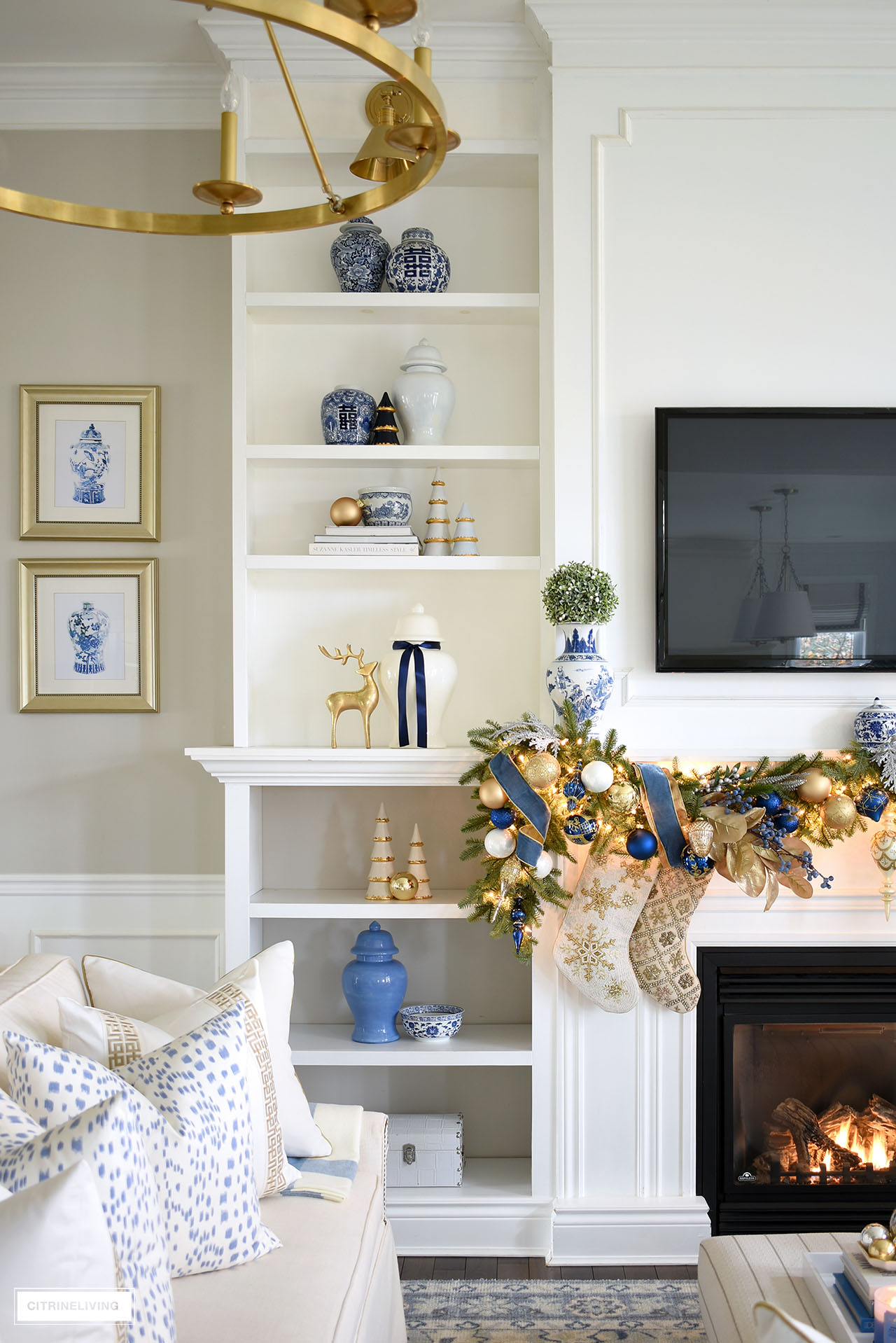 Shelves with blue and white and gold decor styled for christmas, featuring ginger jars, ceramic christmas trees with gold edges, reindeer and blue and white chinoiserie ceramic pieces.