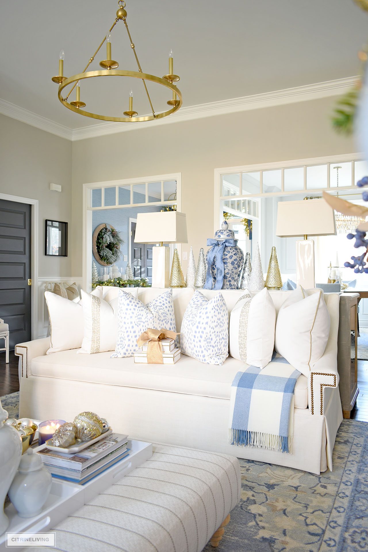 White sofa with designer pillows in white, with gold trim, gold and white fretwork ribbon, and blue and white pillows in a subtle animal print.