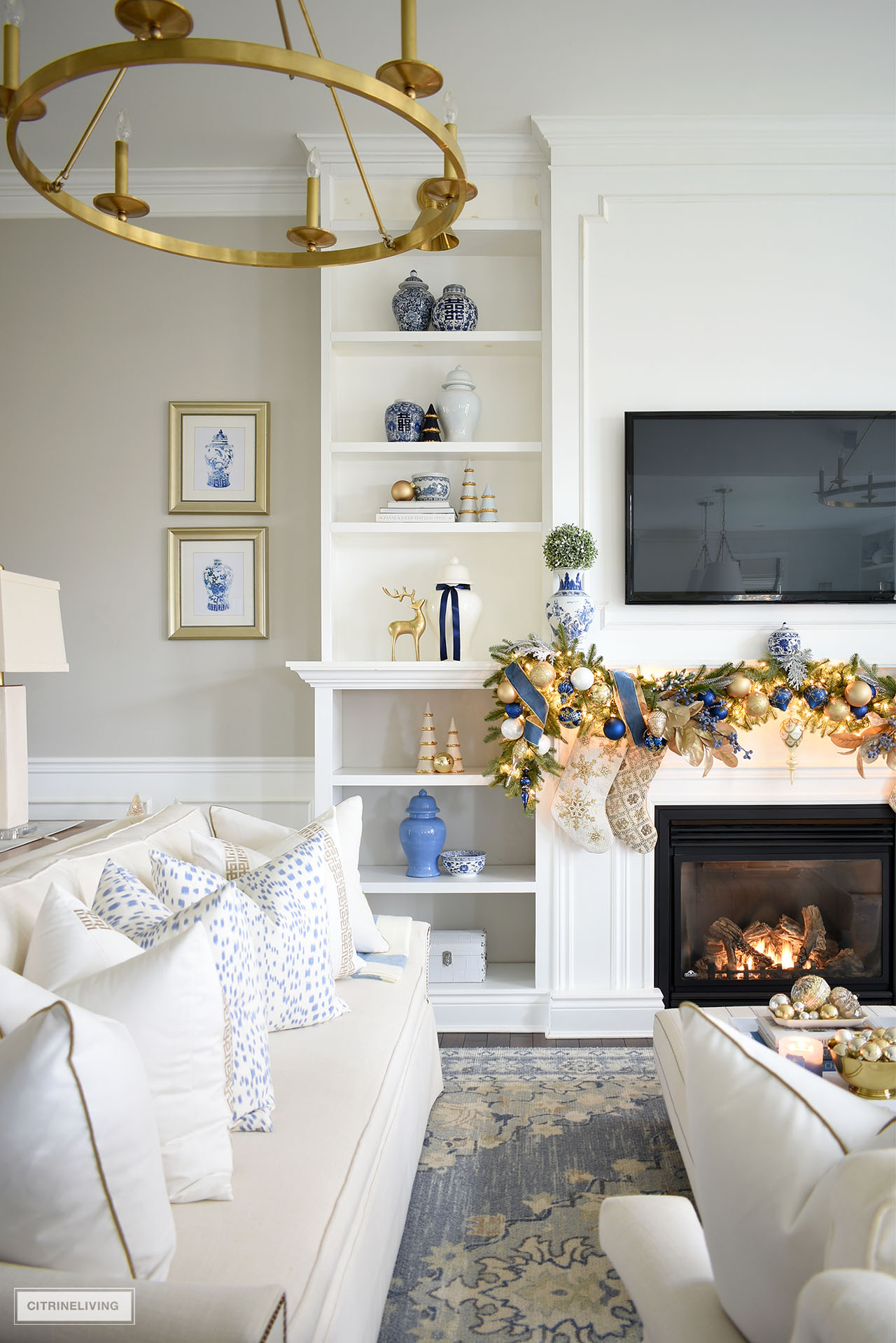 Living room with builtin bookshelves, decorated for Christmas with blue and gold and white accessories.