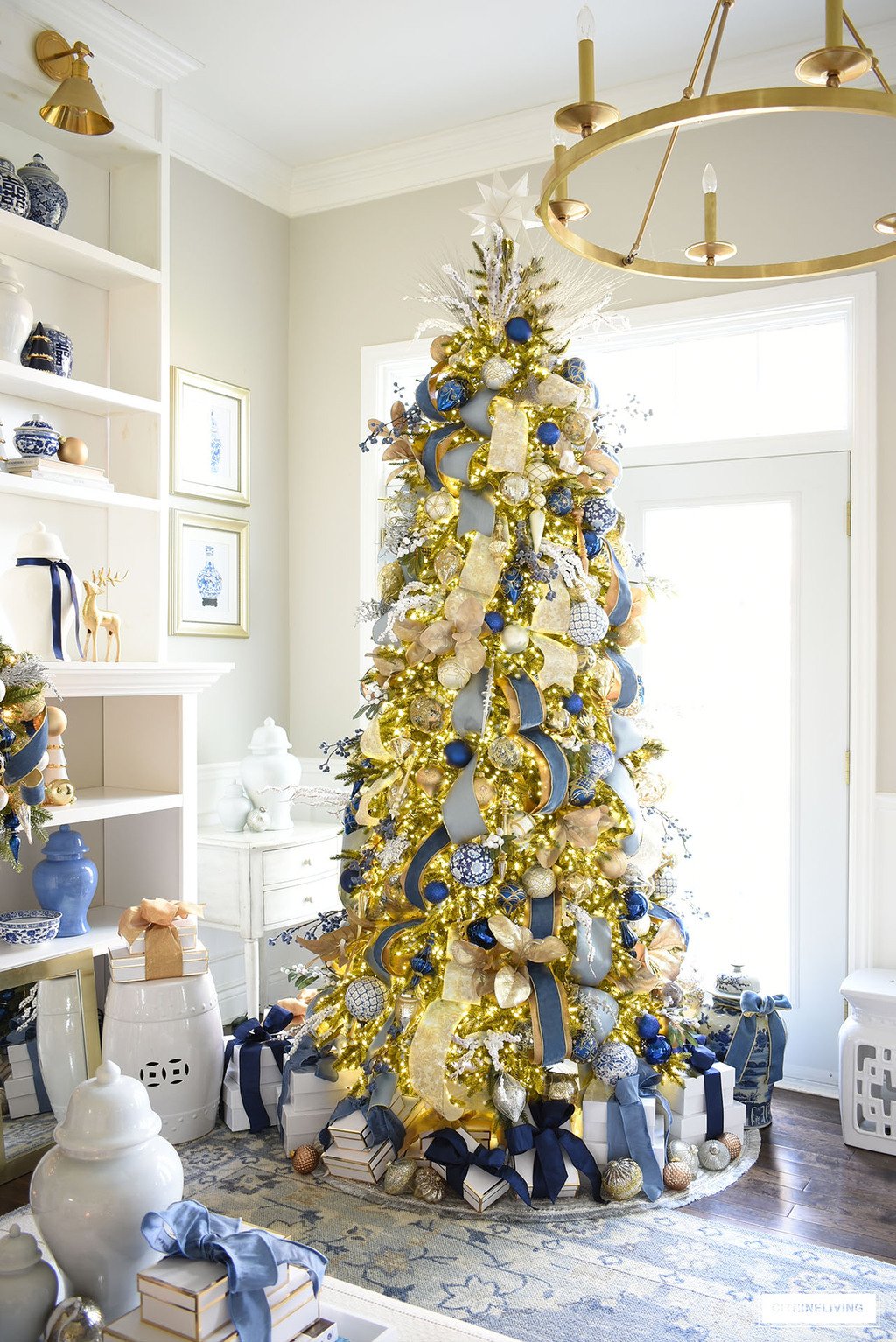 Christmas tree decorated with blue and gold ornaments and ribbon, white gift boxes and blue and gold ribbon.