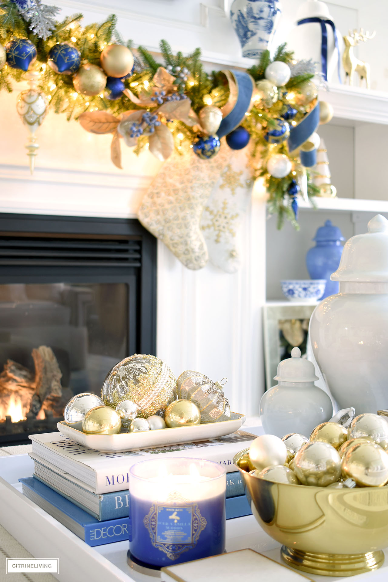 Living room ottoman styled for christmas - a gold bowl and a ceramic tray with silver and gold ornaments, scented candle and ginger jars.