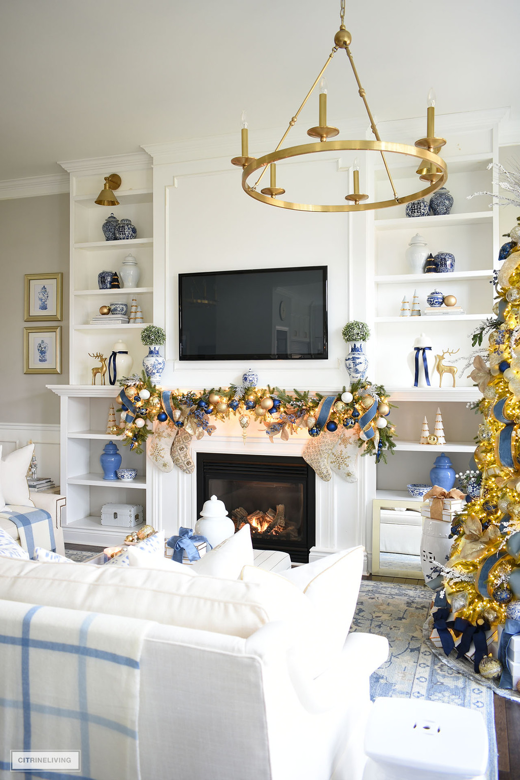 Living room bookshelves and fireplace with a gorgeous swagged garland decorated in elegant blue and gold.