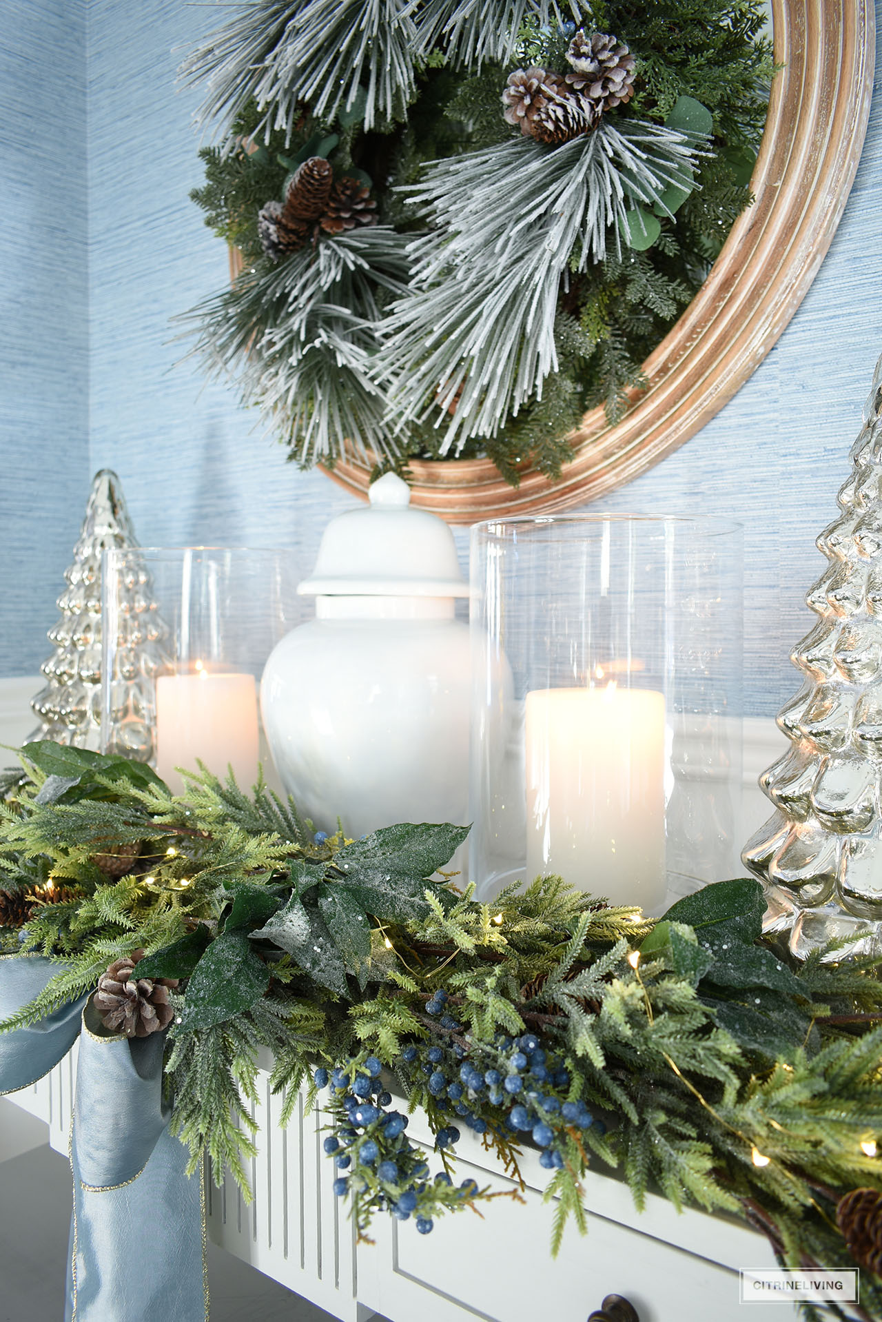 Closeup detail of ginger jar, hurricane lantern, mercury glass trees, styled on a console table for Christmas.