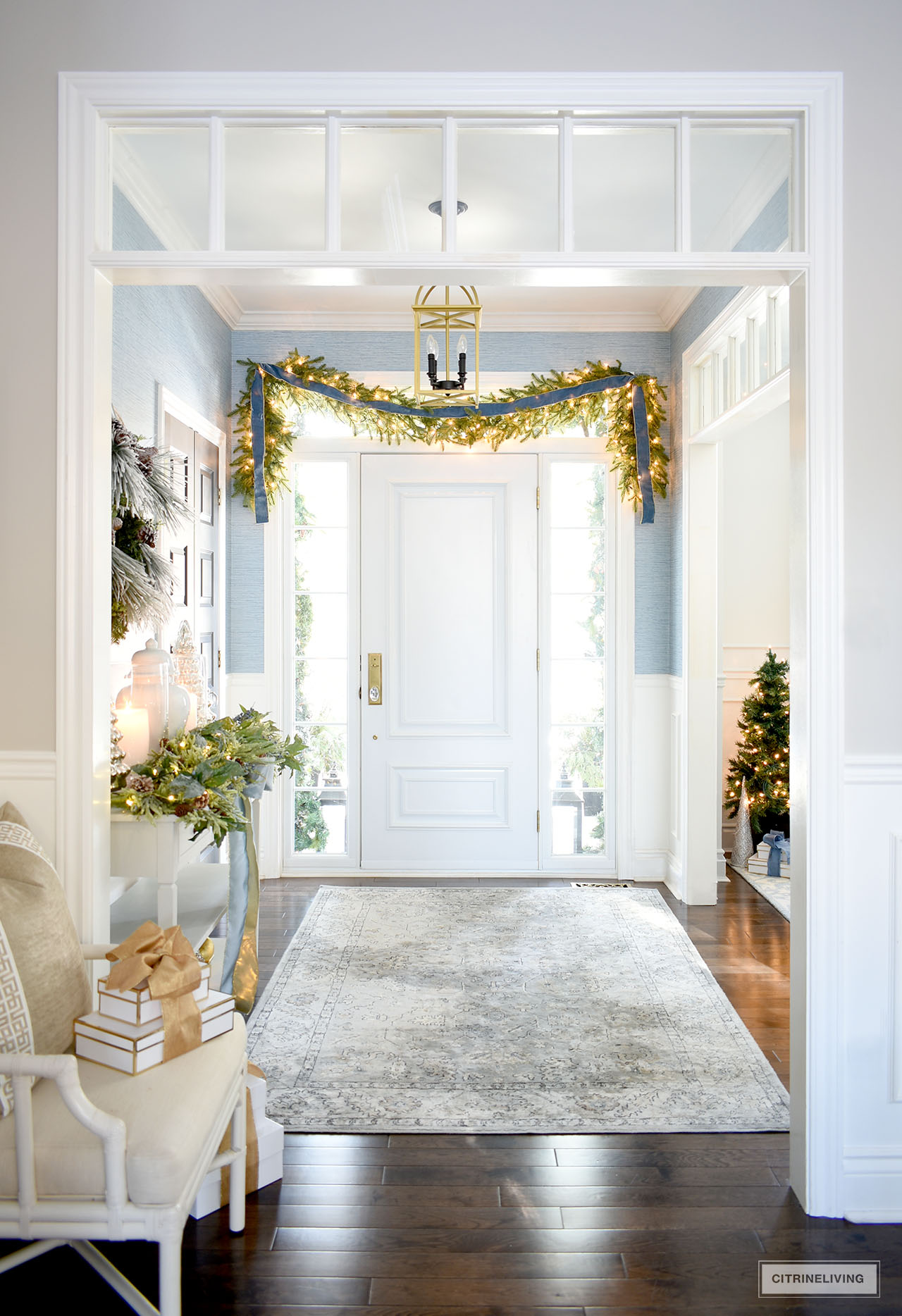 Christmas entryway decor with lush garlands and blue and gold accents. 