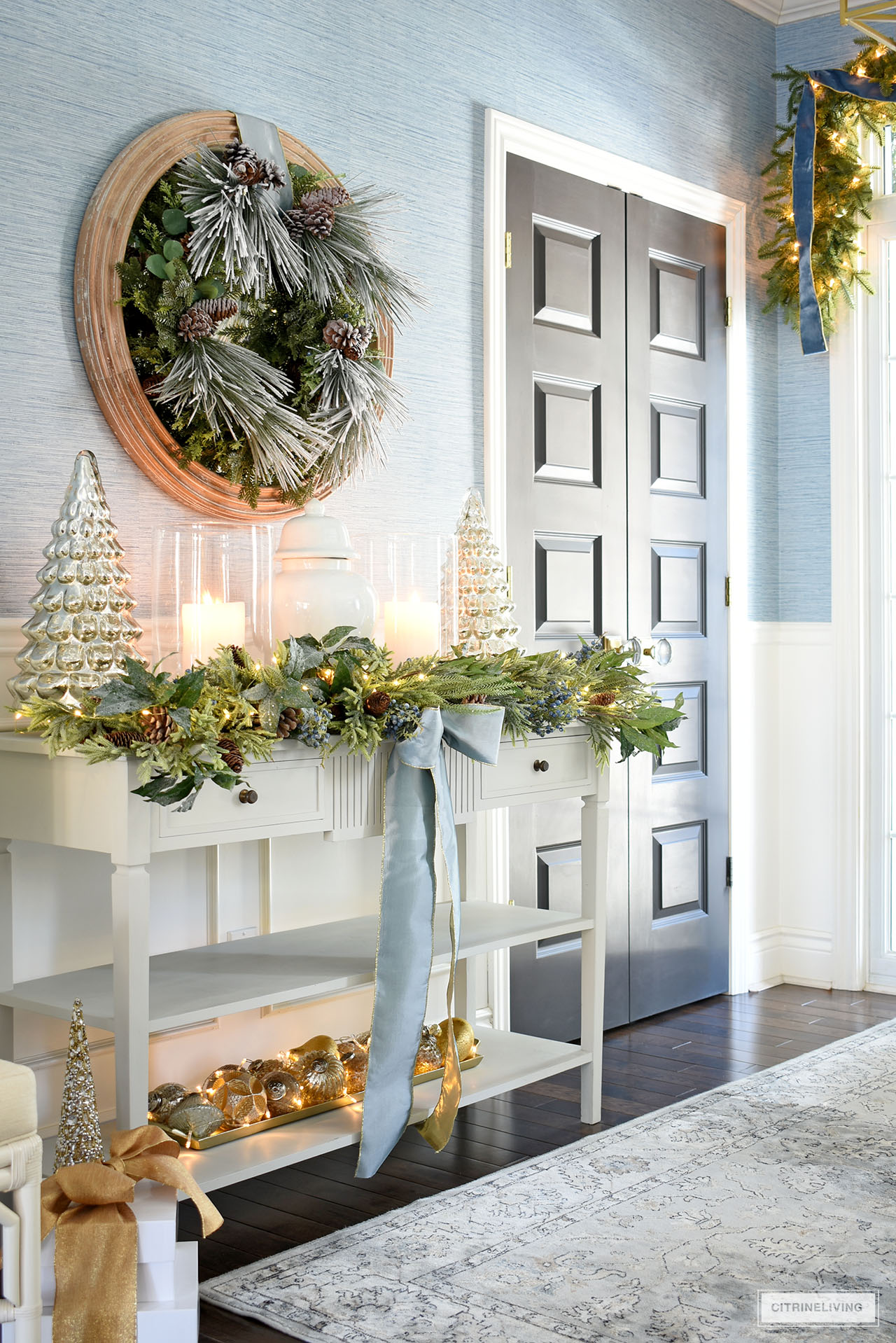 Entryway decorated for Christmas with greenery and blue, gold and silver accents.