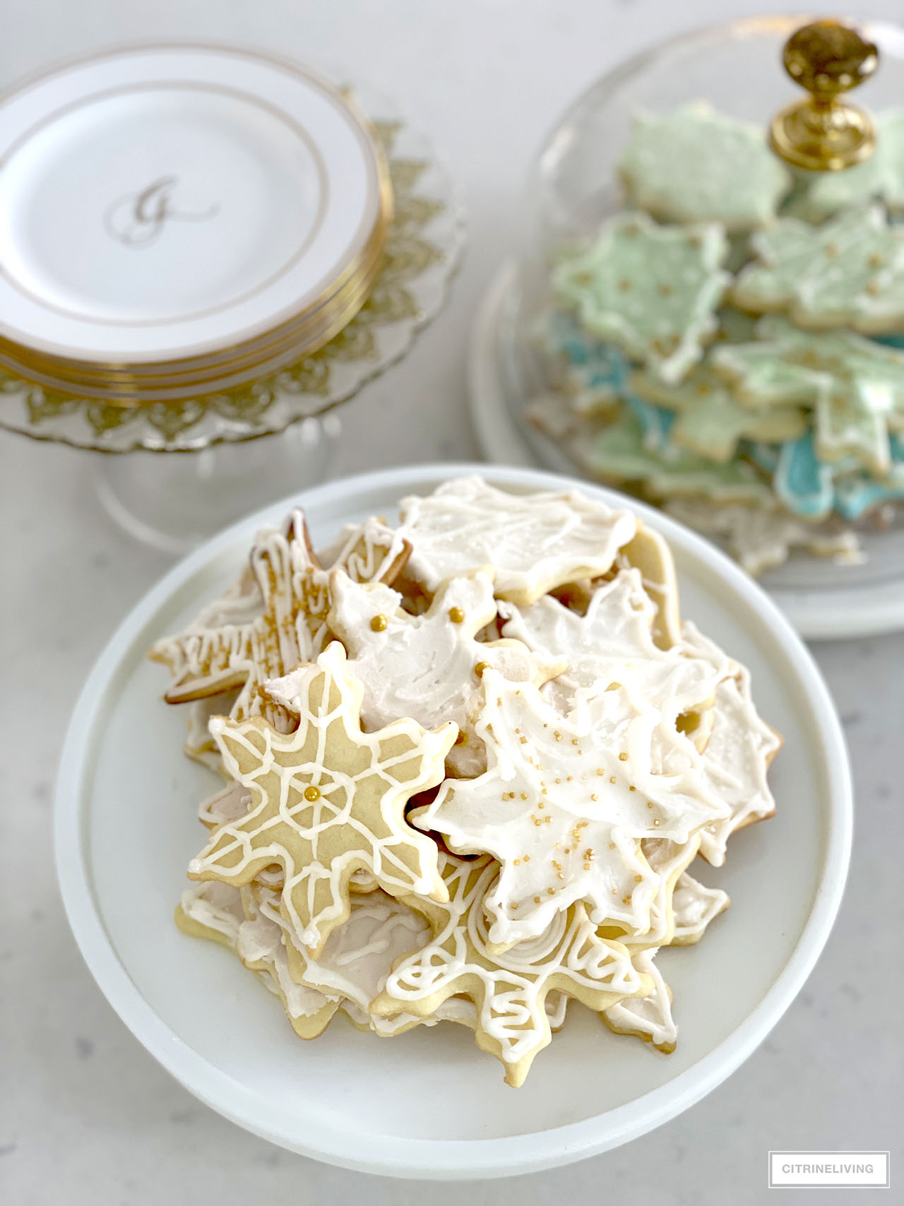 Cakes stands in white, glass and gold hold elegant and beautiful frosted Christmas sugar cookies.