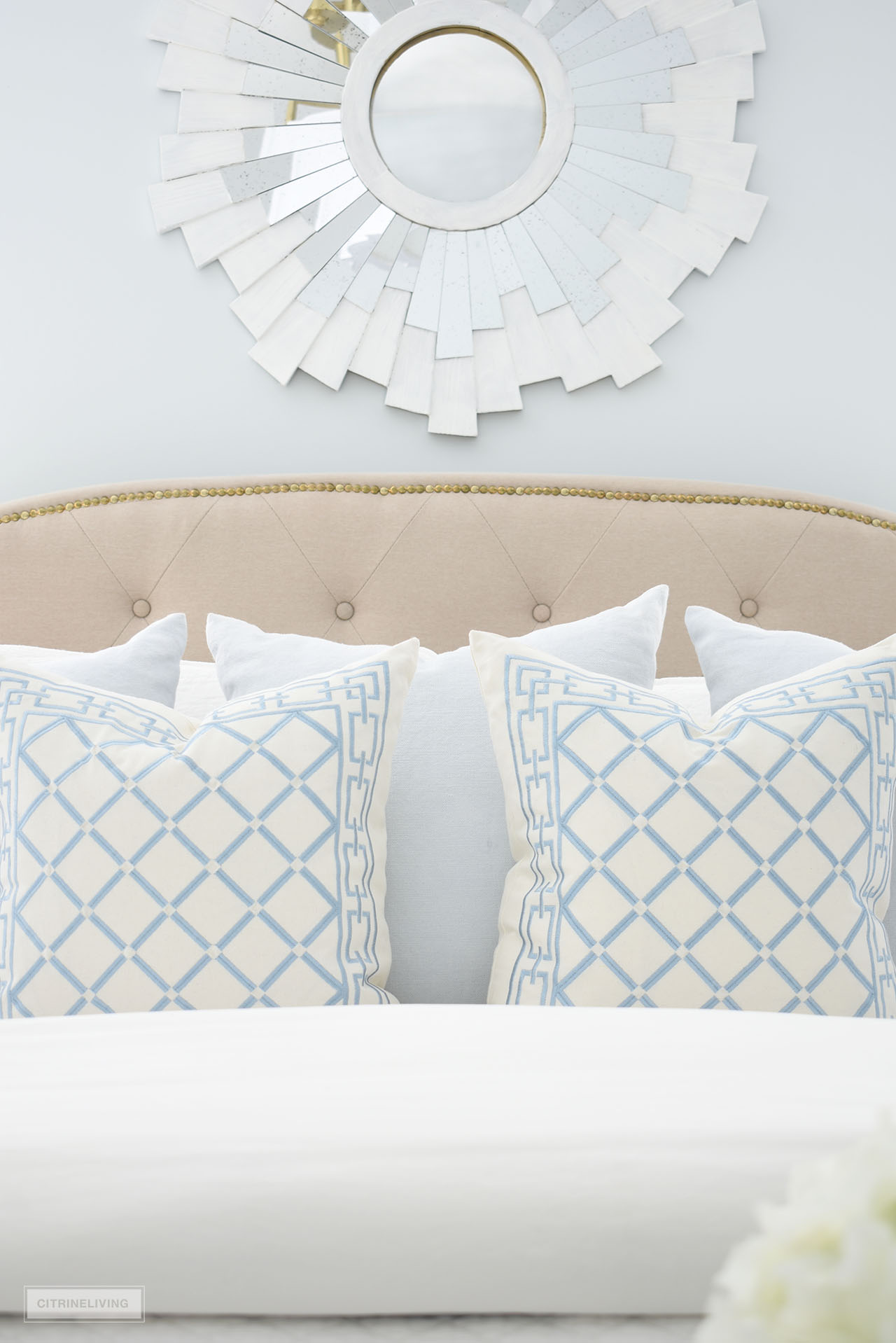 Chic throw pillows in a light blue and white diamond pattern, styled with pretty light blue linen pillows and quilted bedding.