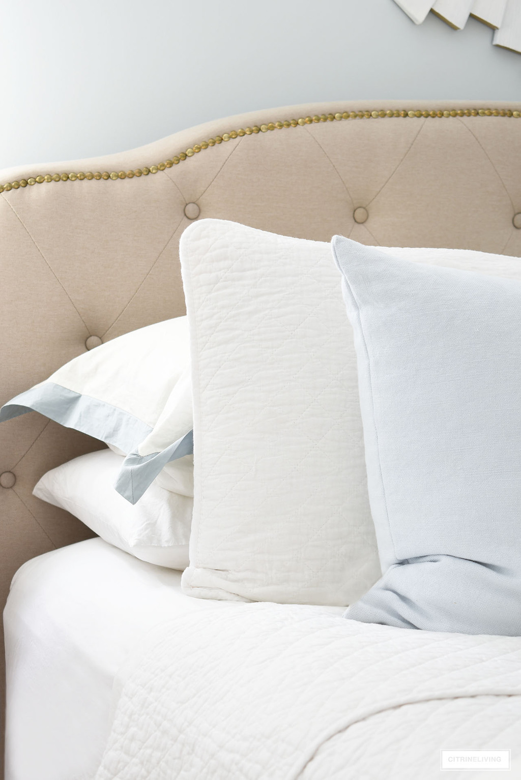 Layers of quilted bedding, white sheets and light blue throw pillows.