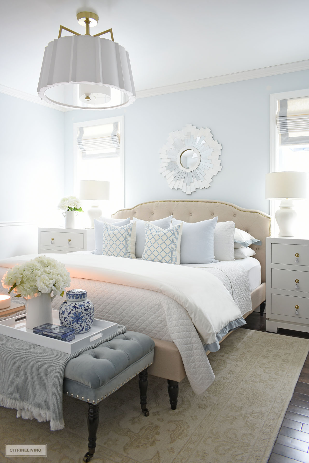 Calming bedroom decor in soft blue and white. Layers of quilted bedding, throw pillows and pretty accents create a serene bedroom.