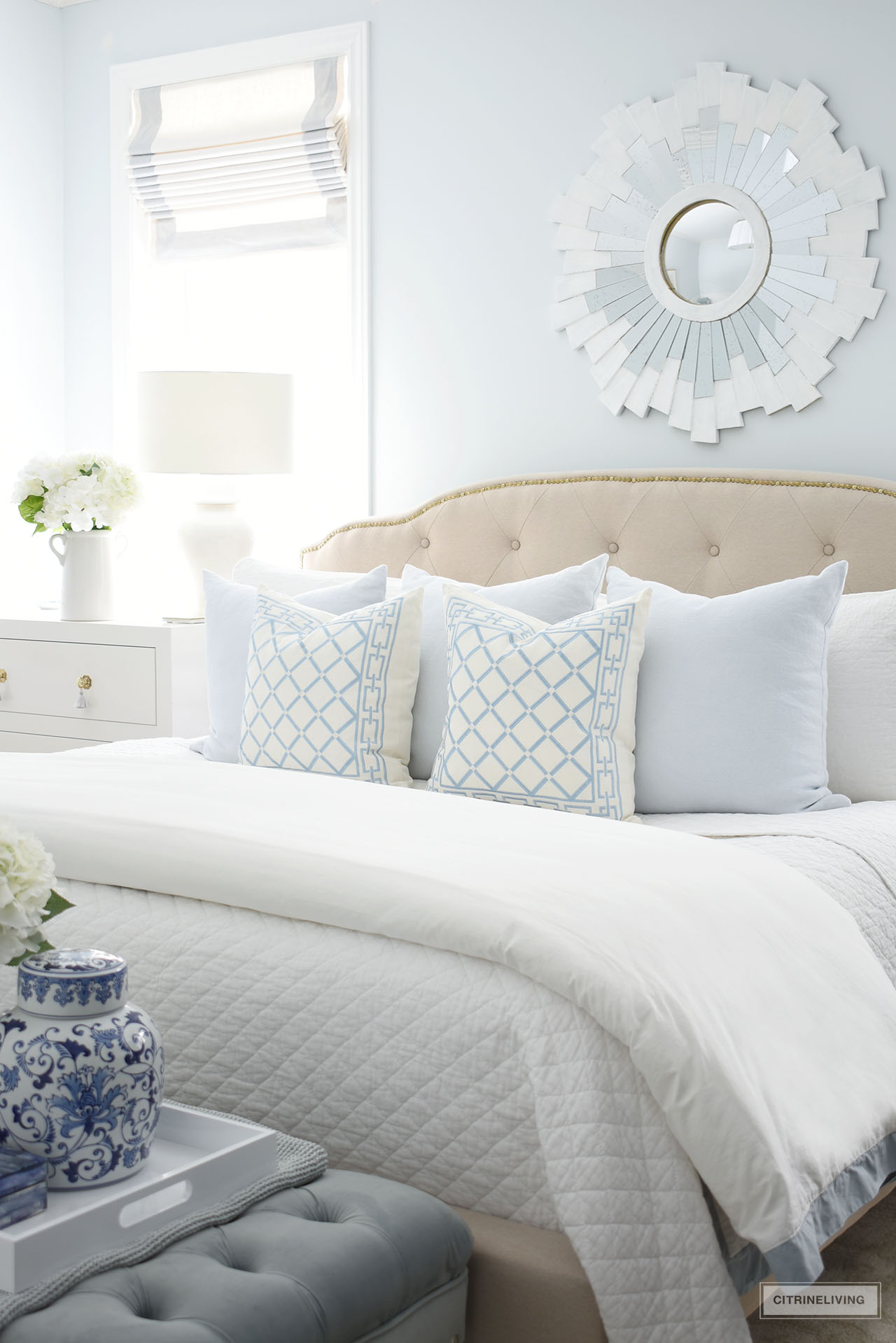 Beautiful bed layered with soft blue and white throw pillows and quilted bedding.