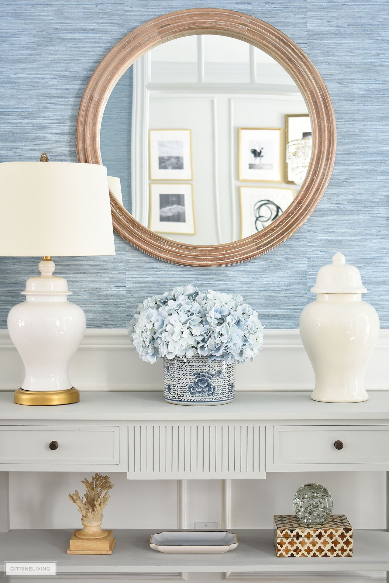 A symmetrical display styled for spring with white ginger jars, a blue and white planter and light blue hydrangeas is elegant and chic.