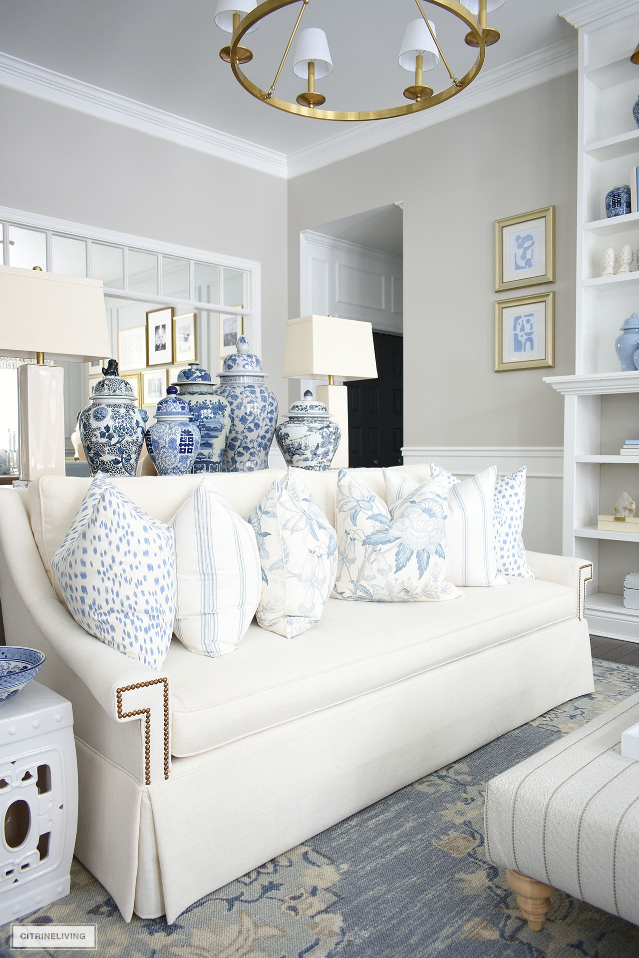 White sofa styled for spring with blue and white pillows in floral, stripe and animal print patterns.
