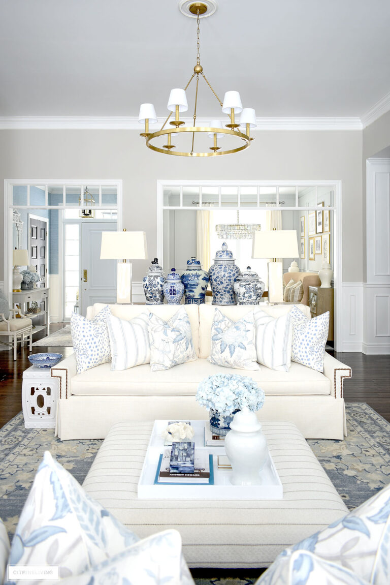 Spring living room decor in blue and white styled with ginger jars, floral and striped pillows and blue and white chinoiserie accents.