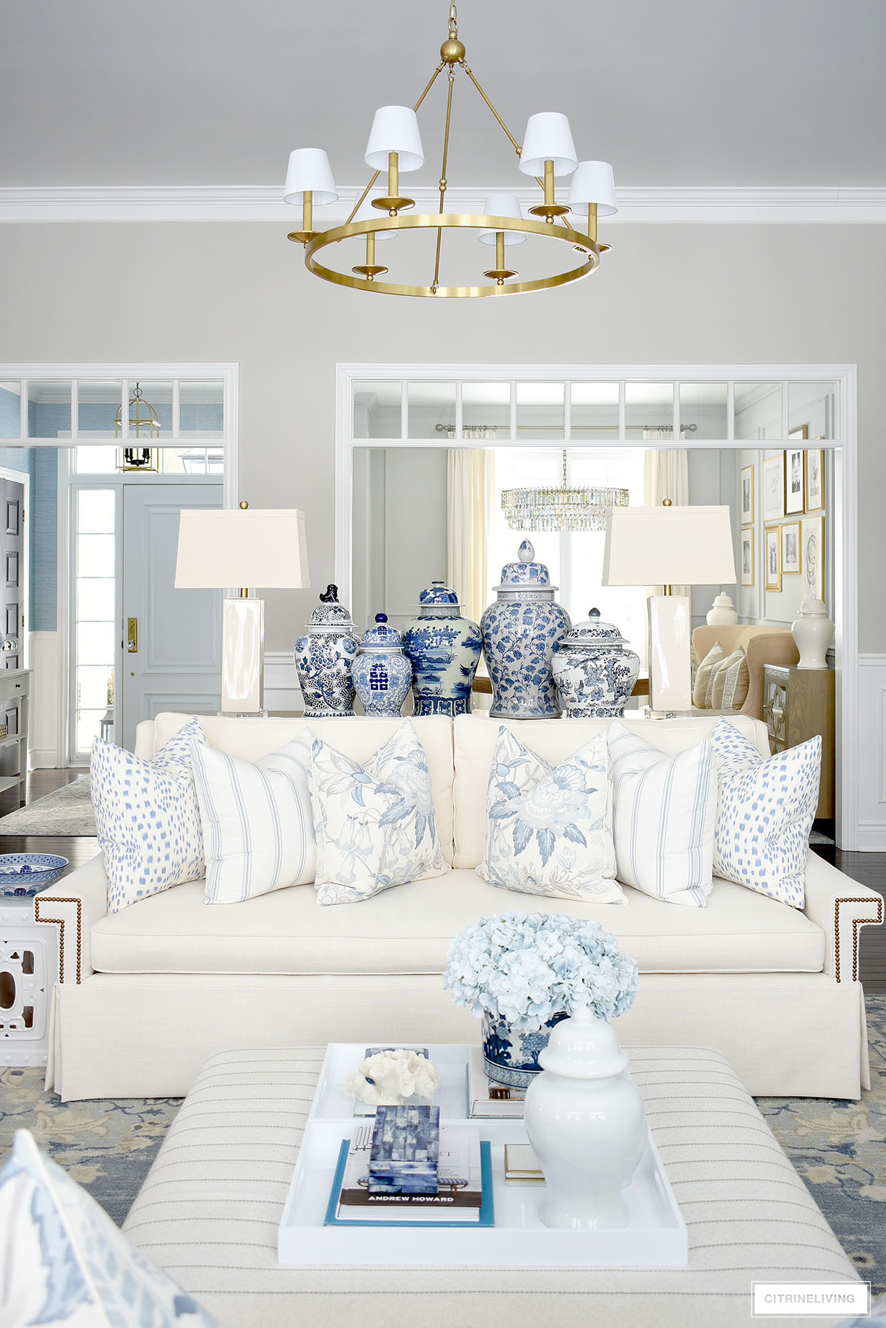 Living room decorated for spring with blue and white pillows, blue and white ginger jars and faux flowers.