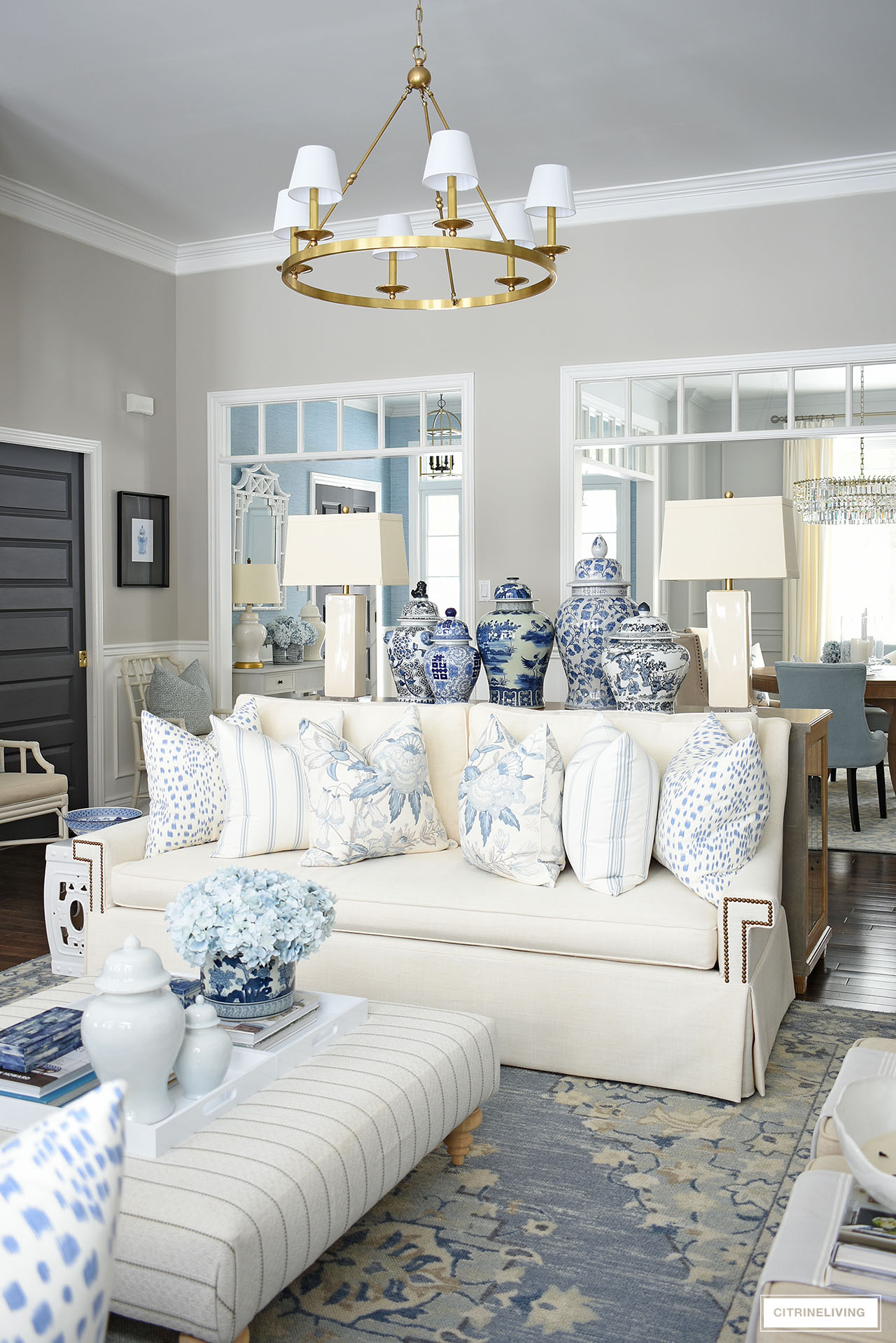 Spring living room decorated with beautiful blue and white pillows, ginger jars and faux flowers.