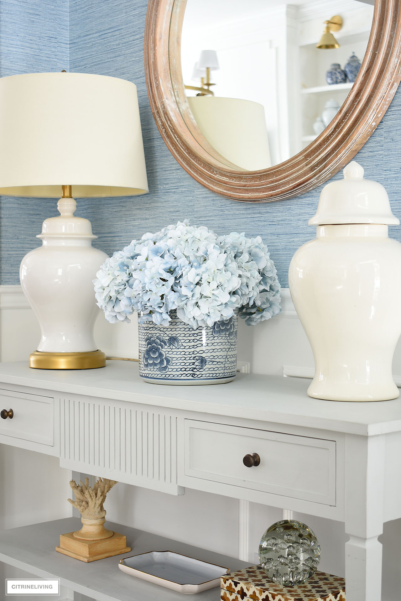 A beautiful blue and white planter with light blue hydrangeas is a chic and elegant focal point on this classic console table.