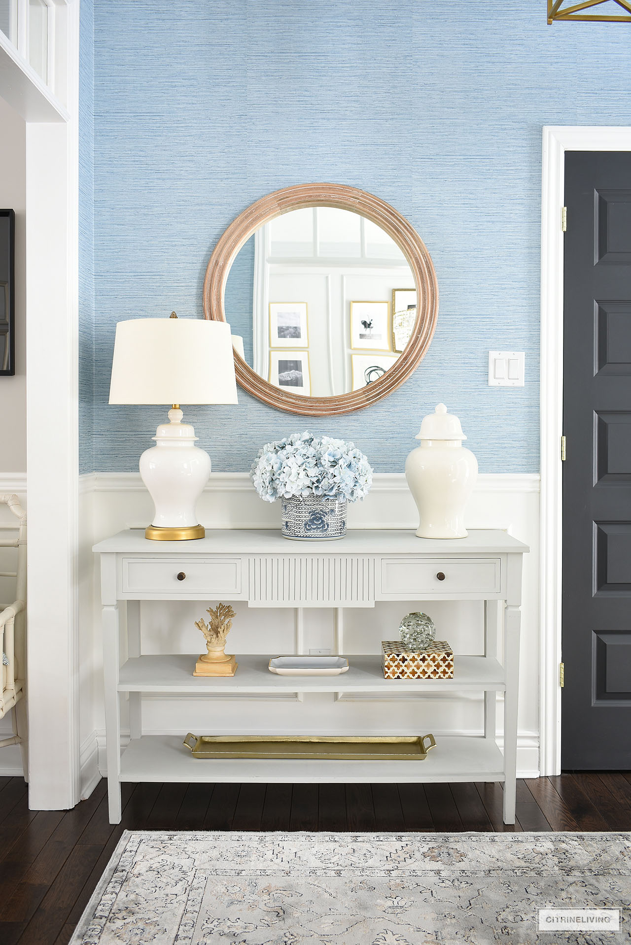 Entryway console table styled for spring with white ginger jars and ginger jar lamp, light blue hydrangeas and neutral accessories.