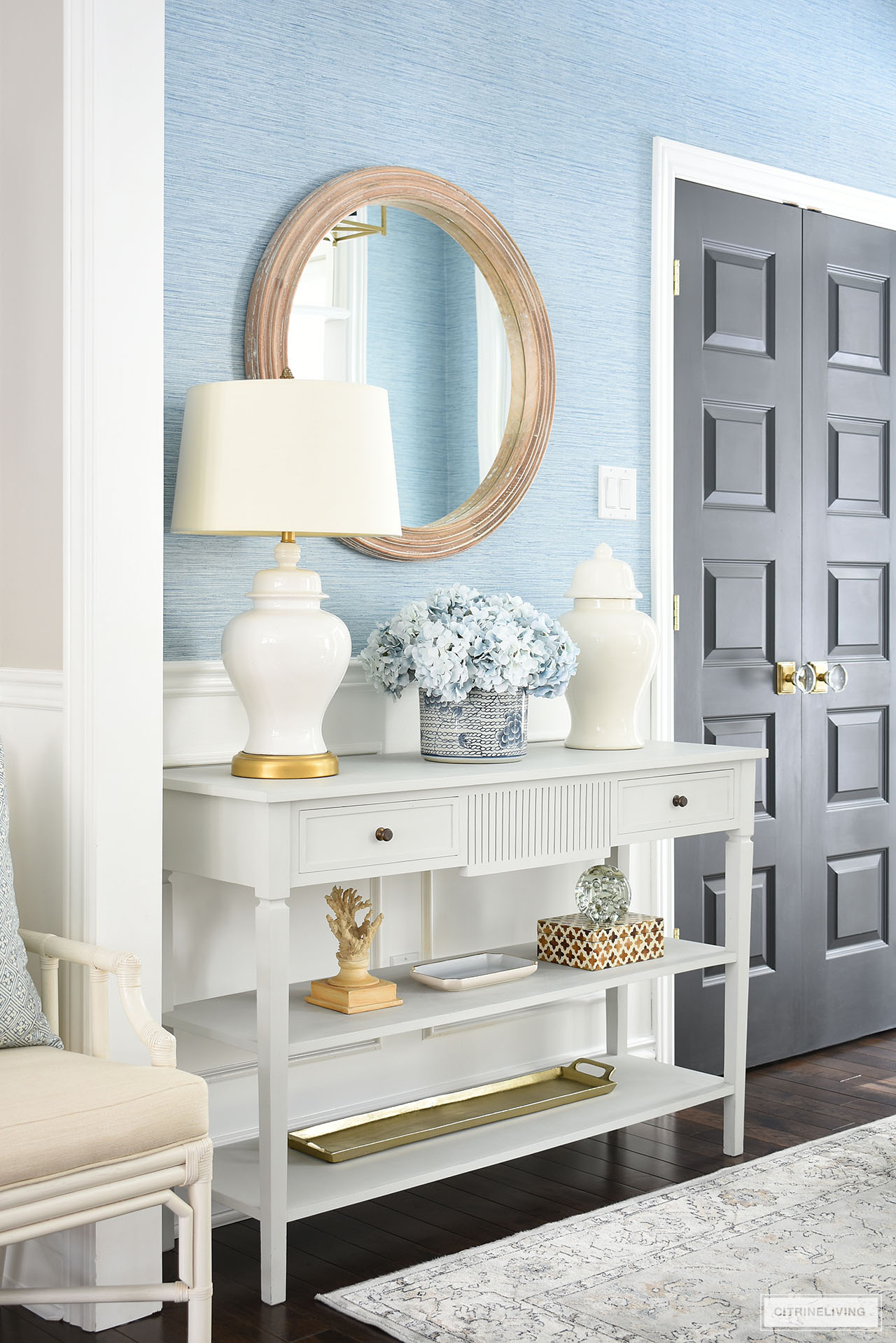 Console table styled with spring decor featuring light blue hydrangeas, white ginger jars, and natural closed accessories.