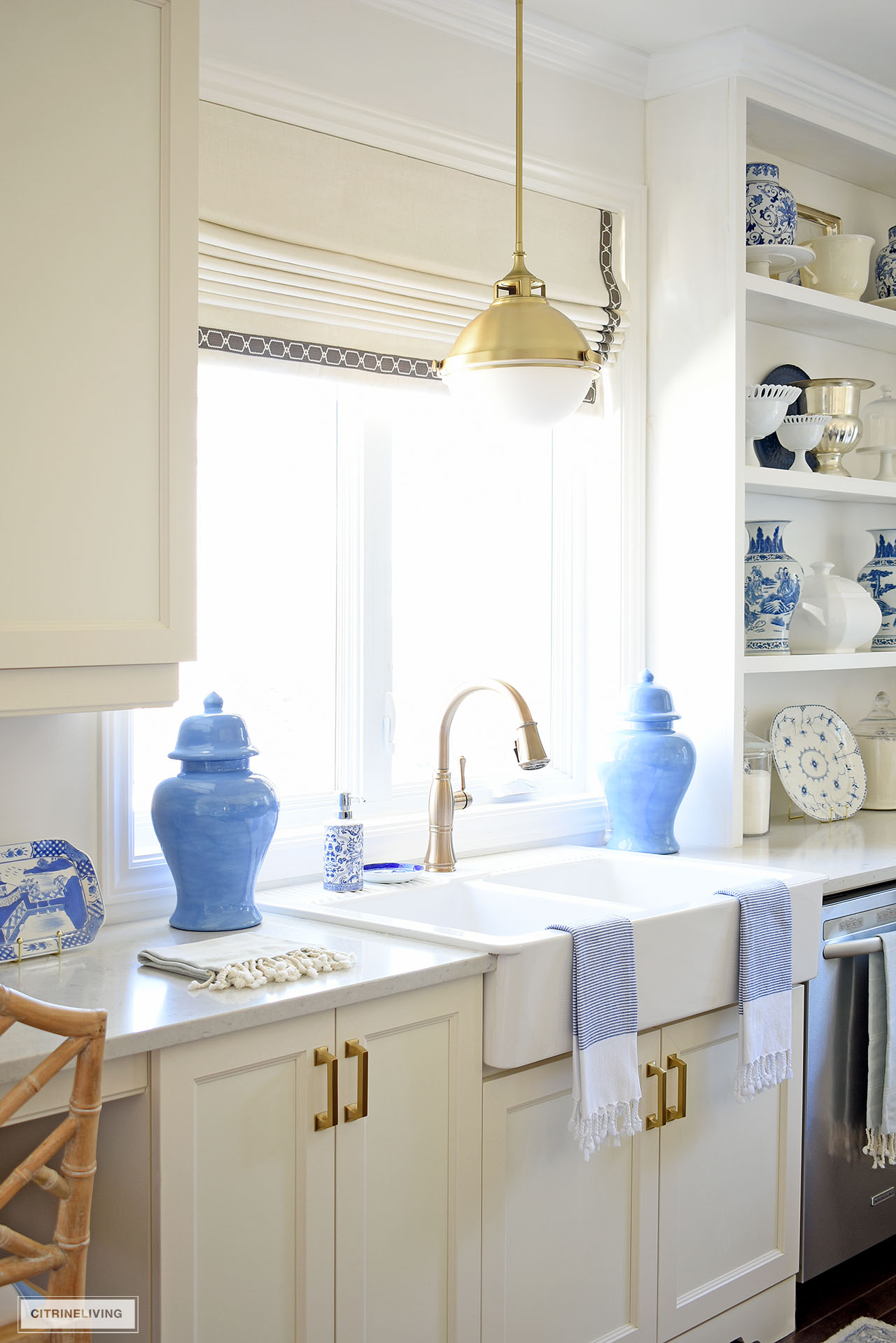 White kitchen farm sink decorated with blue ginger jars, pretty tea towels and blue and white accents.