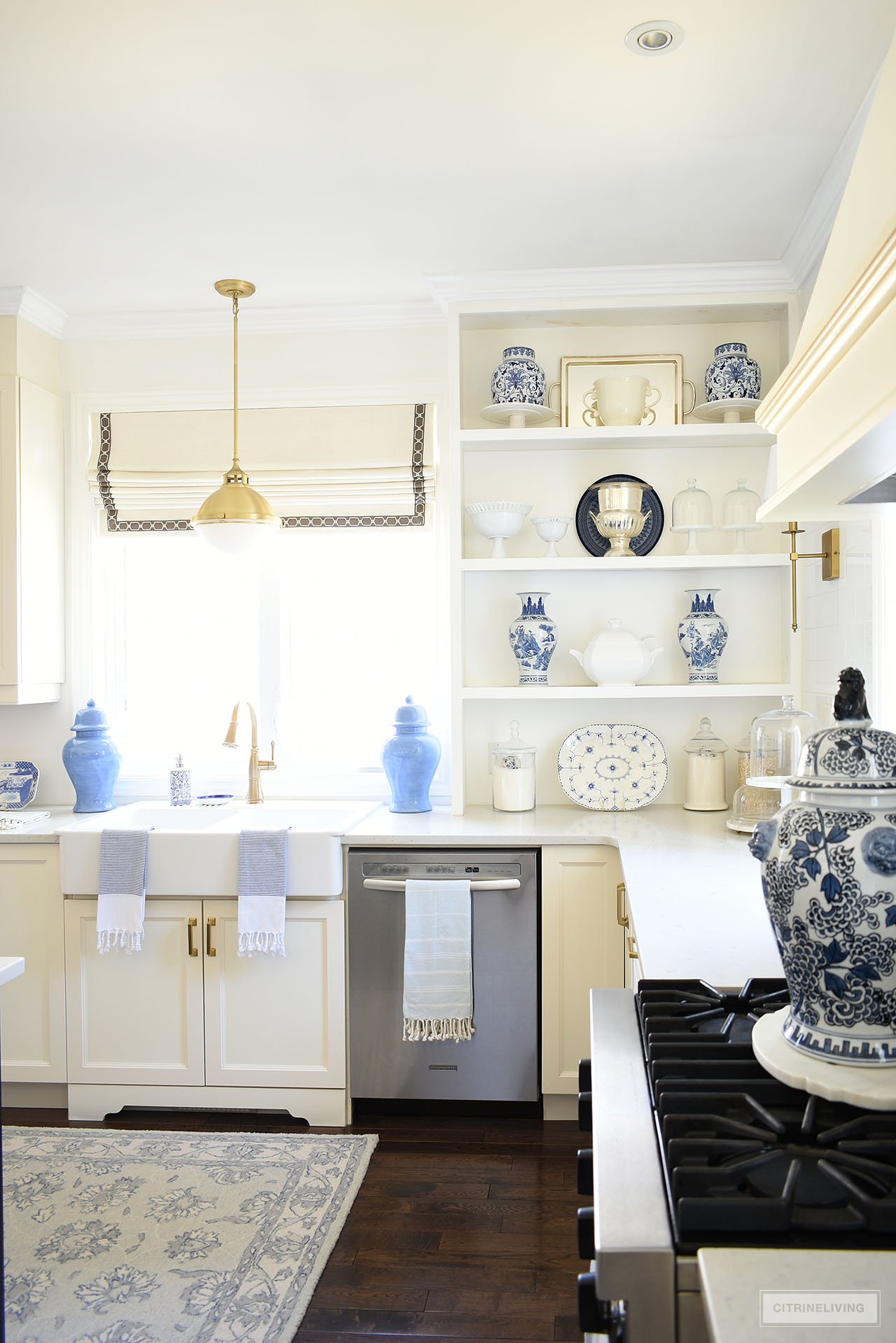 Open kitchen shelves and white farm sink decorated for spring with a beautiful blue and white pottery and dish collection.