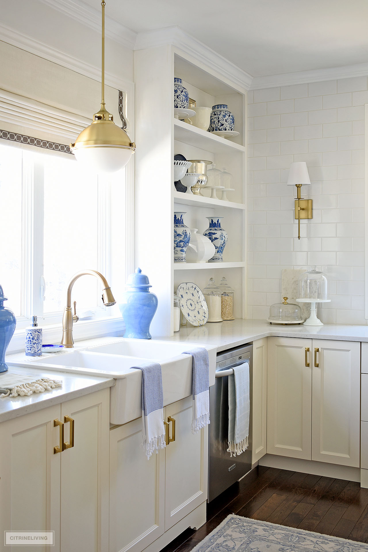 Kitchen sink and open shelving styled  for spring with beautiful blue and white ginger jars, vases and white and glass dishes and accessories.