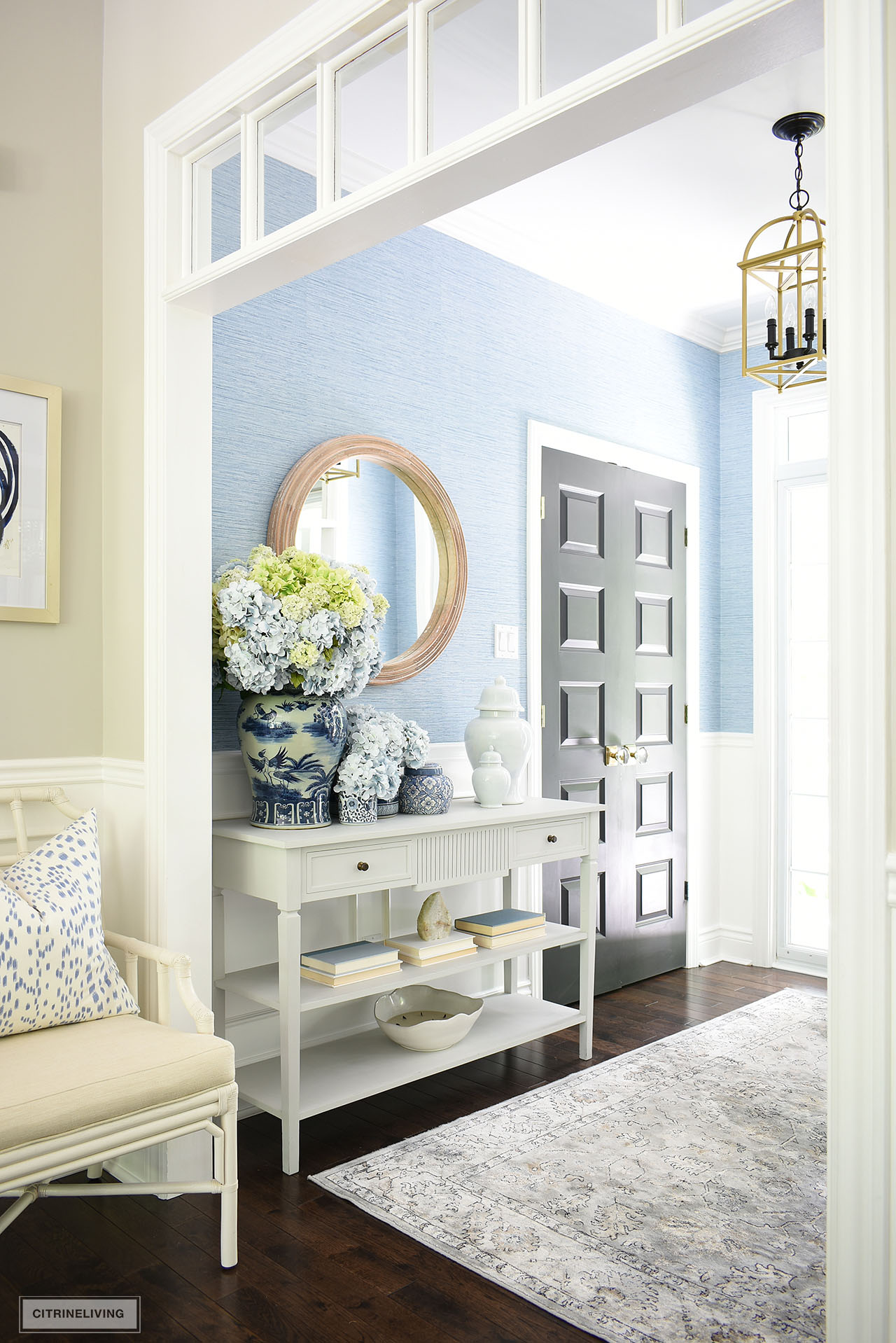 An entryway decorated for summer with classic blue and white vases and jars, styled with beautiful faux hydrangeas.