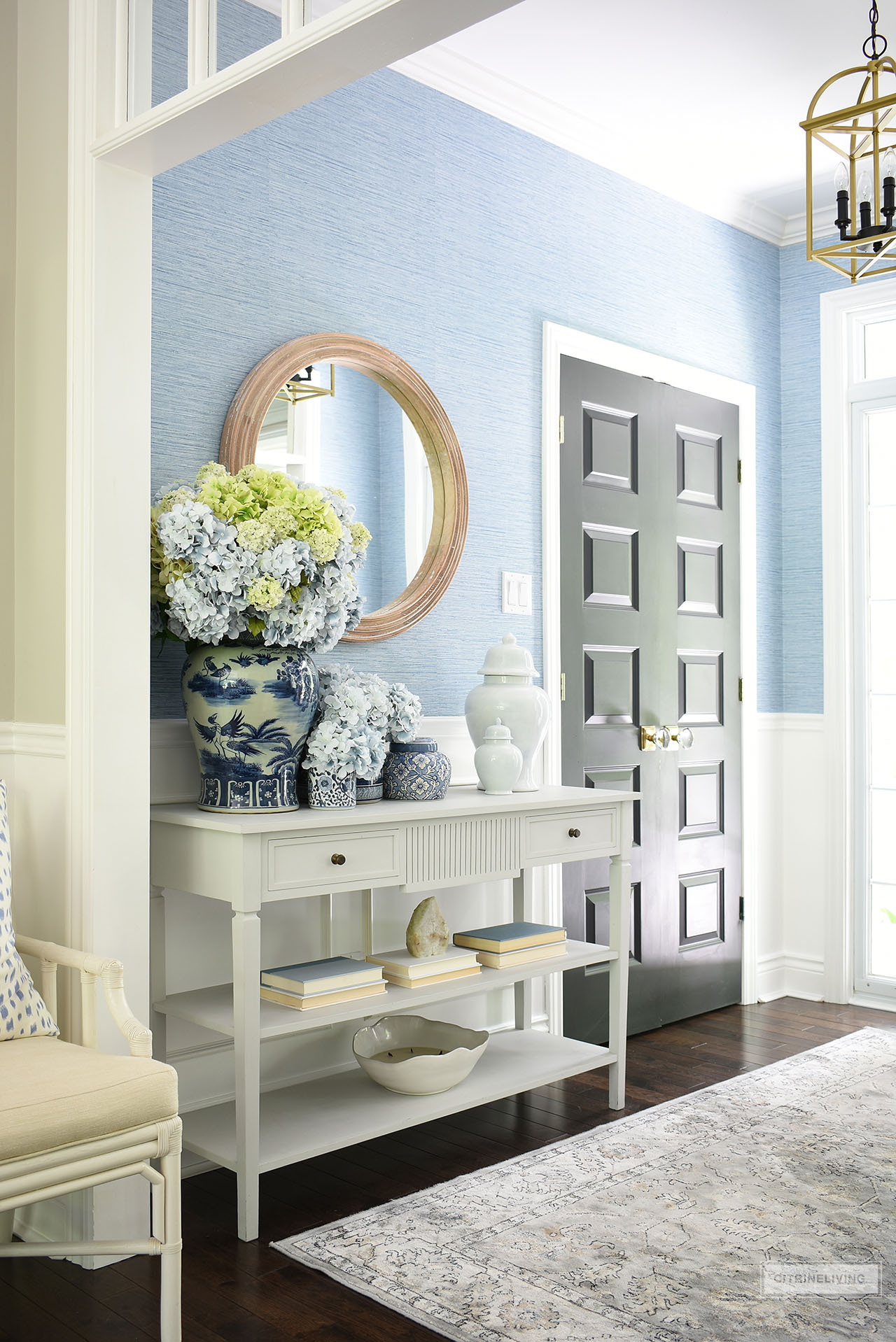 Entryway decorated for summer with beautiful blue and white ginger jars, blue and green hydrangeas in a full, large arrangement and simple accessories styled on a clean-lined console table.