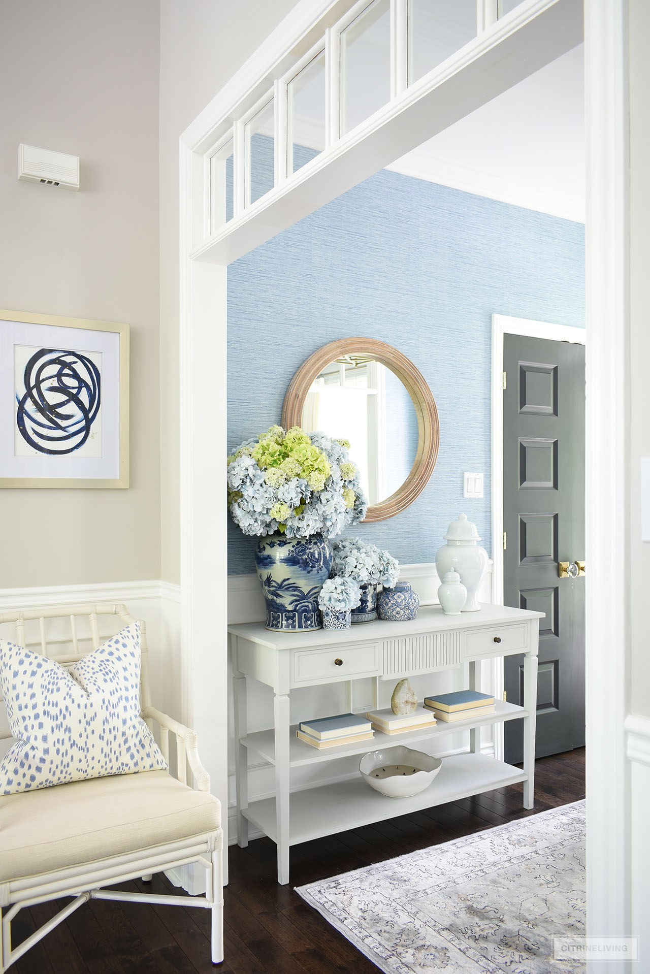 A look into a classic entryway decorated for summer with blue and white ginger jars arranged with beautiful blue and green hydrangeas, accented with simple accessories.