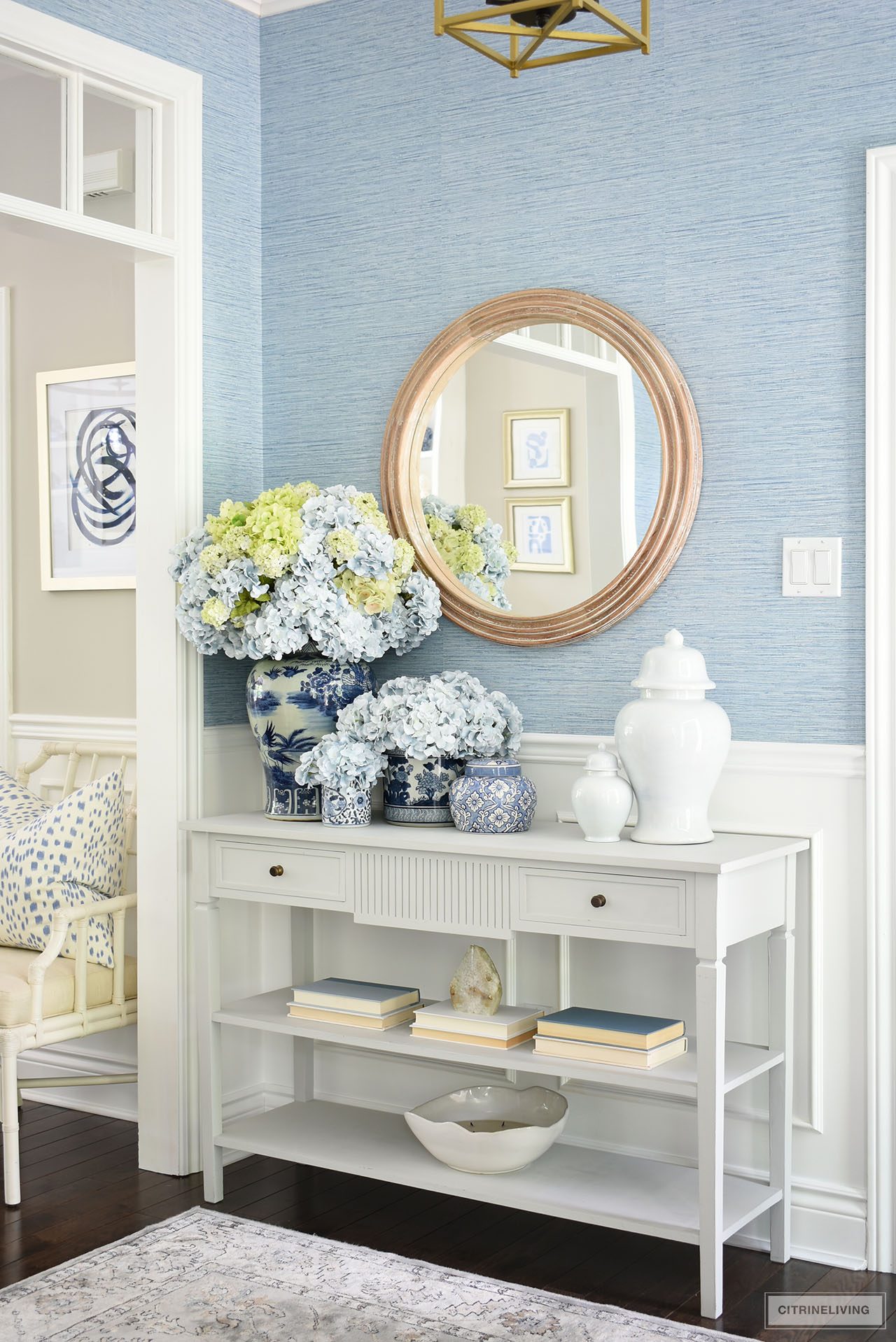 Entryway console table decorated in blue and white chinoiserie, ginger jars and simple accessories. A full, large floral arrangement with blue and green hyrdrangeas makes a stunning and bold statement.