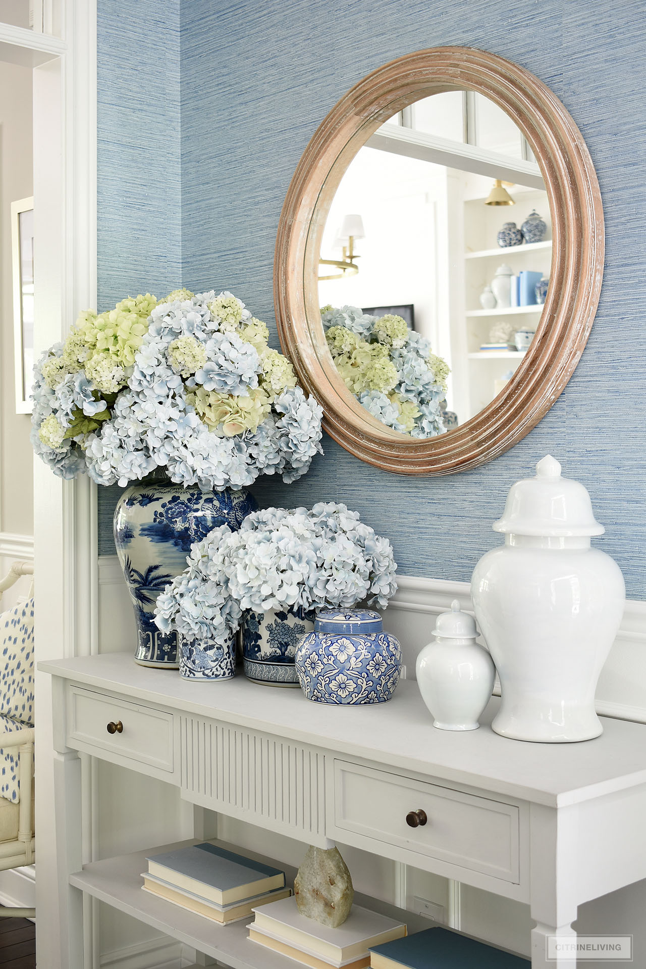 A closeup view of a gorgeous summer console table display with blue and white ginger jars and containers filled with light blue and green hydrangeas.