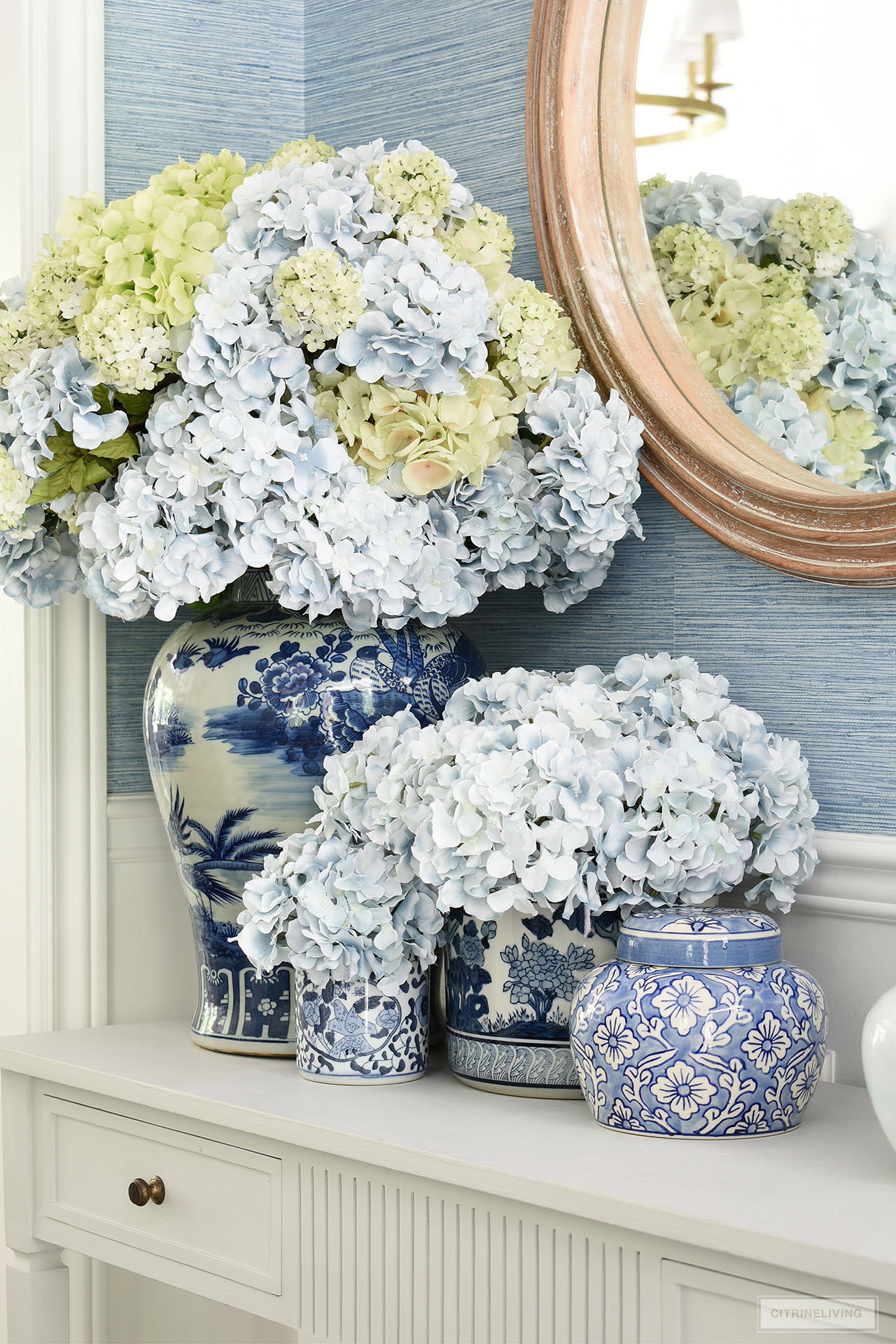 A stunning display of light blue and green hydrangeas arranged in blue and white ginger jars and vases creates a classic and chic summer look.