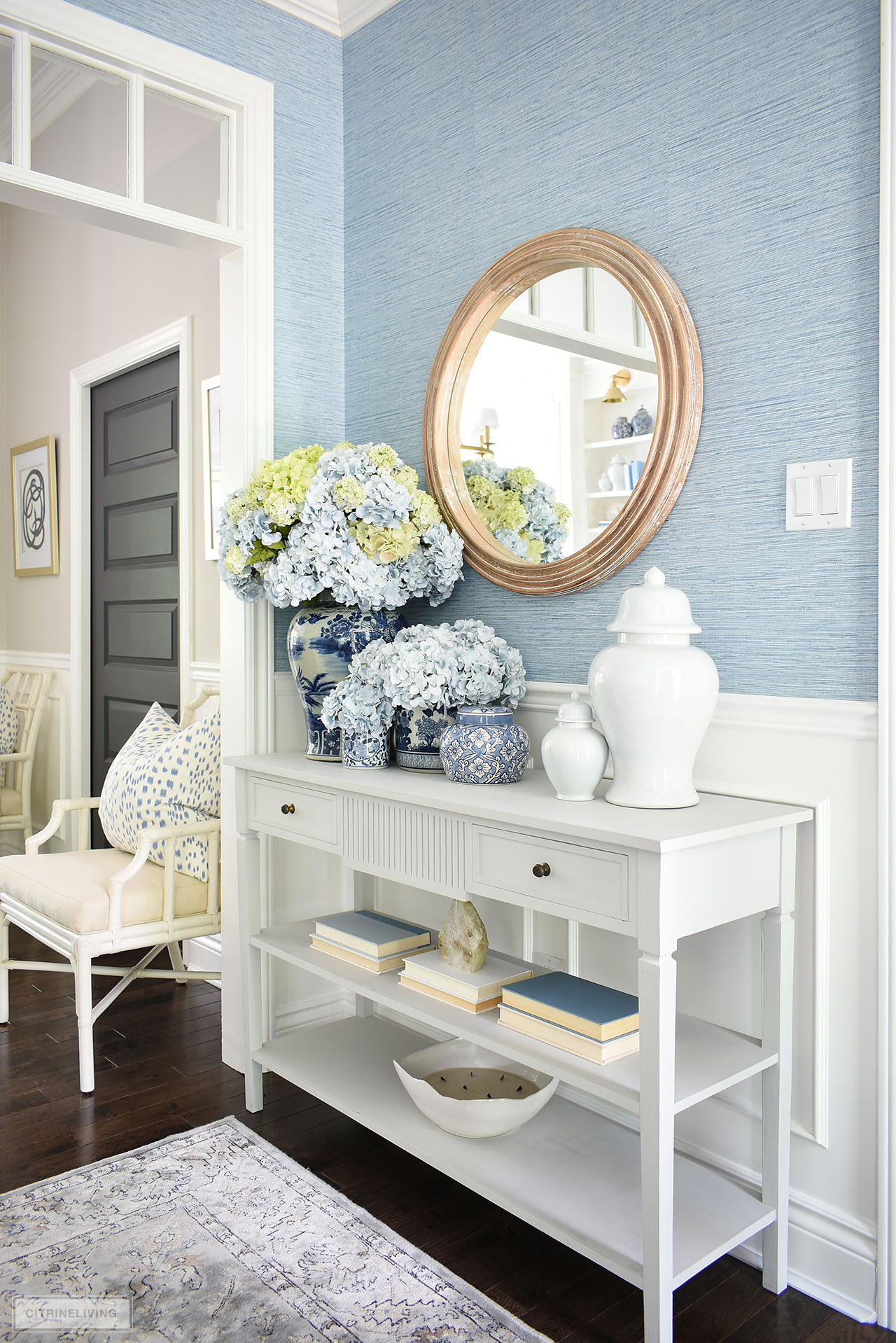 A gorgeous entryway decorated for summer with blue and white ginger jars styled with blue and green hydrangeas in a gorgeous full arrangement.