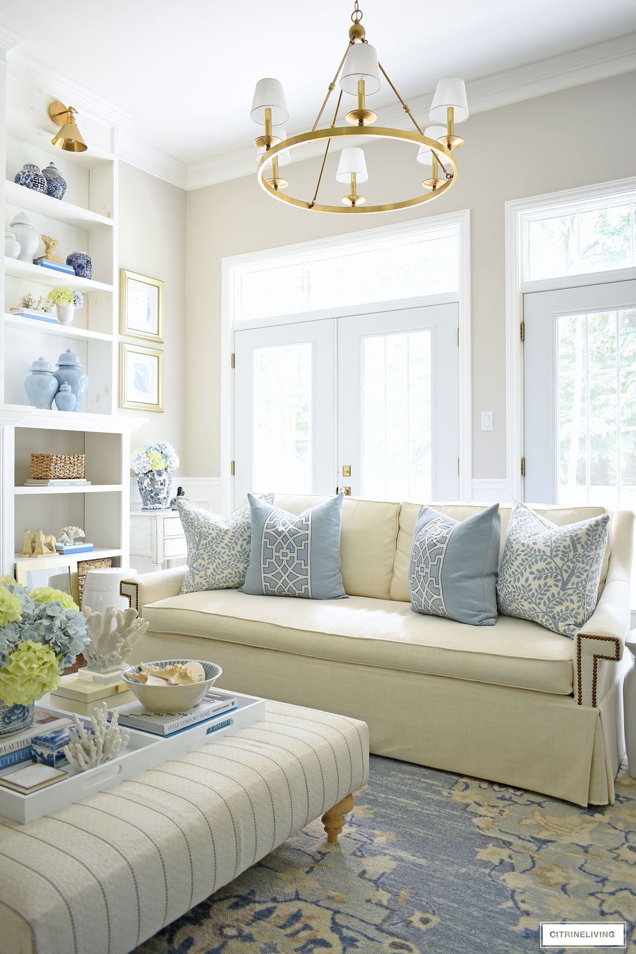 Gorgeous summer decorated living room with soft blues, warm whites. Faux hydrangea arrangements in light blue and green grace different areas around the space.
