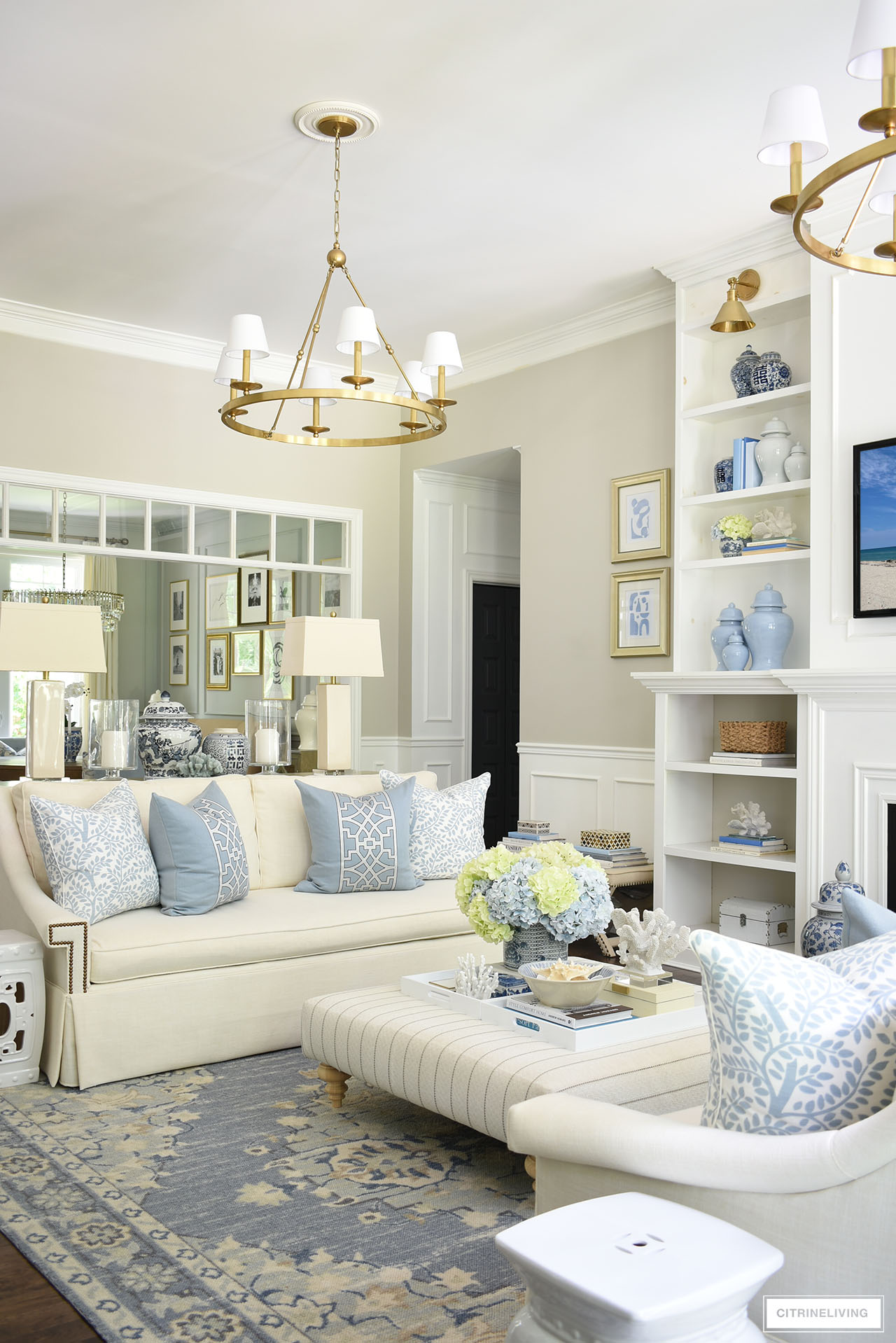 Beautiful, traditional living room decorated for summer in soft blues and white, with light blue and light green hydrangeas, coastal accents and ginger jars.