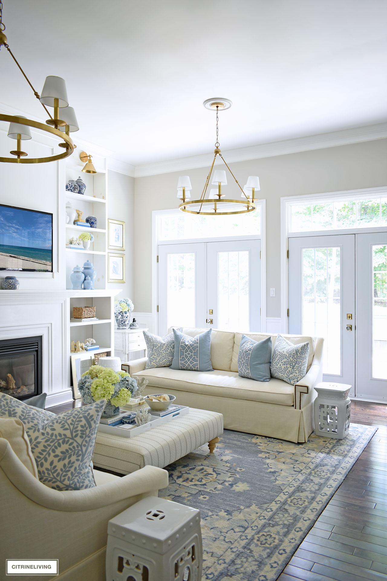 Elegant living room decorated for summer with a gorgeous light blue and white color palette, hydrangeas, ginger jars, woven accents and coastal accessories.
