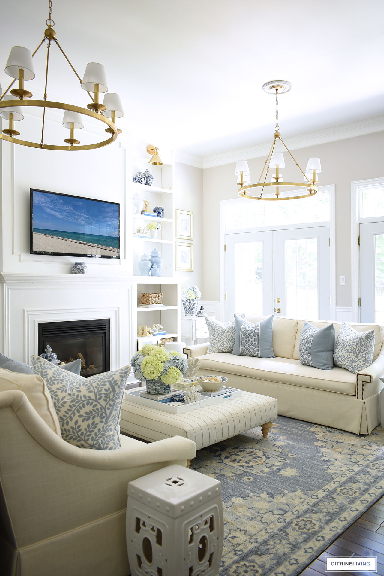 Living room decorated for summer in a soft blue and warm white color palette.