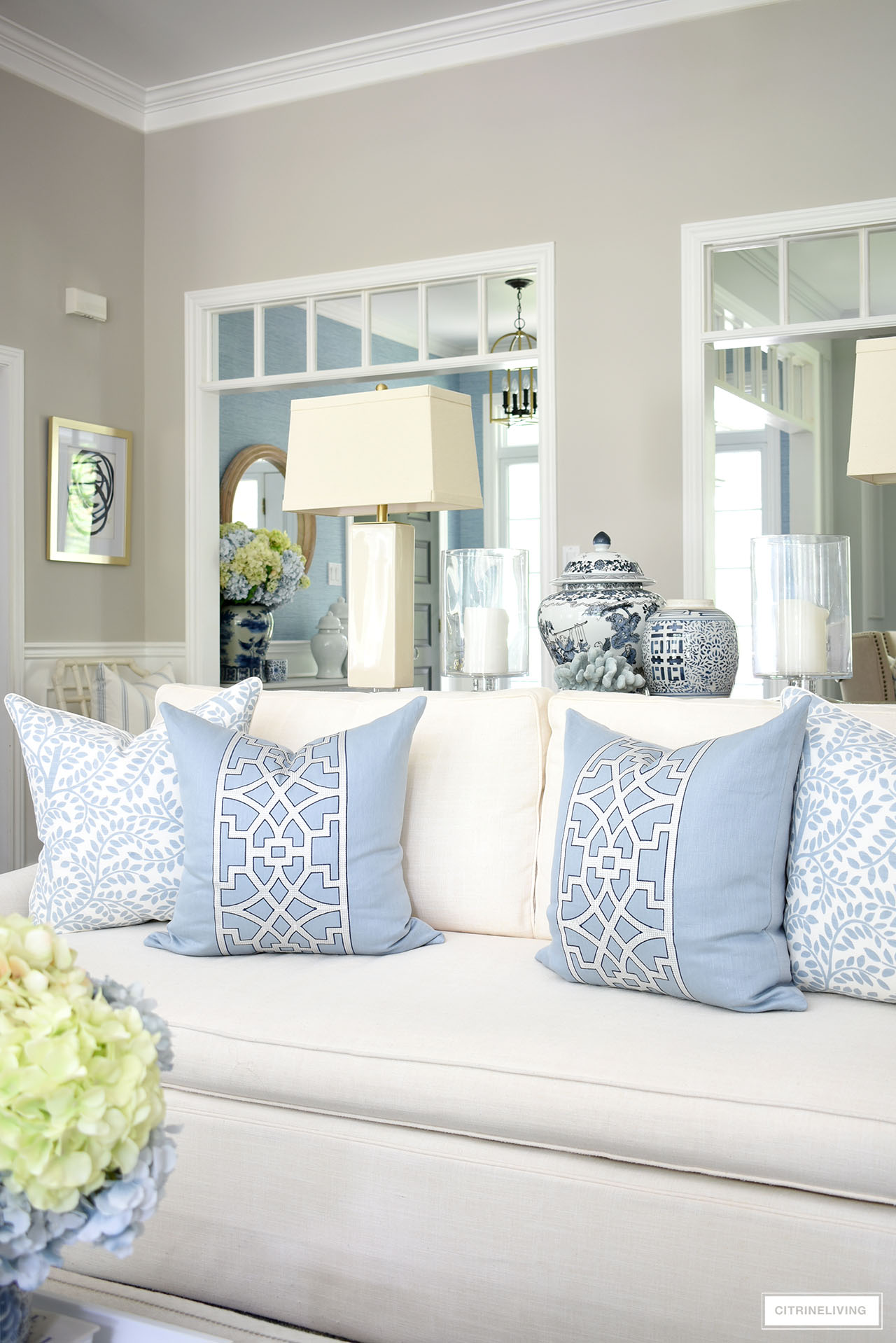 Gorgeous pillows styled on a white sofa for summer - blue with a white trellis motif and an overall leaf pattern in a light blue on a white ground.