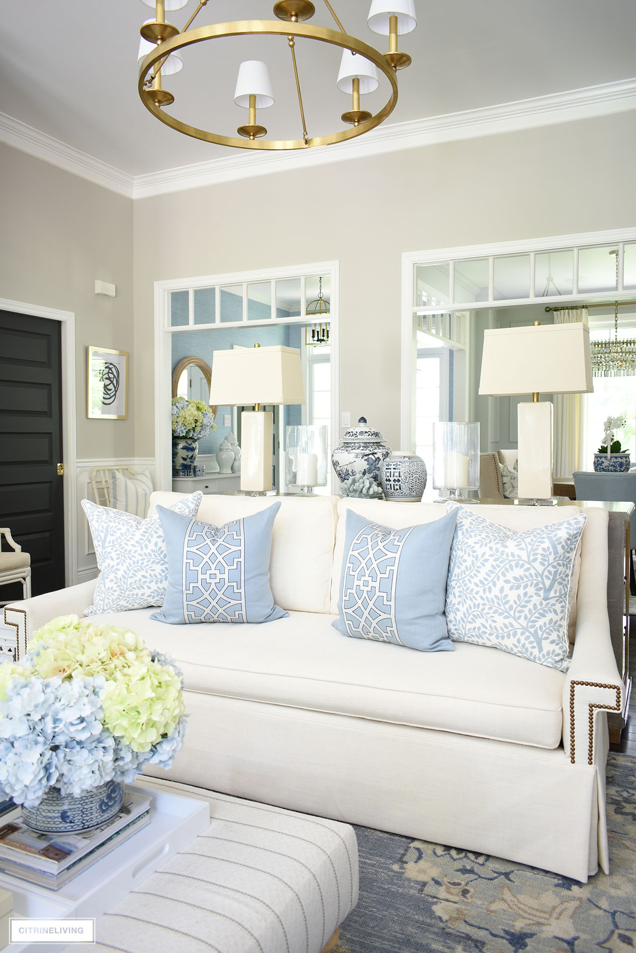 White sofas styled for summer with beautiful light blue and white pillows in chic chinoiserie prints.