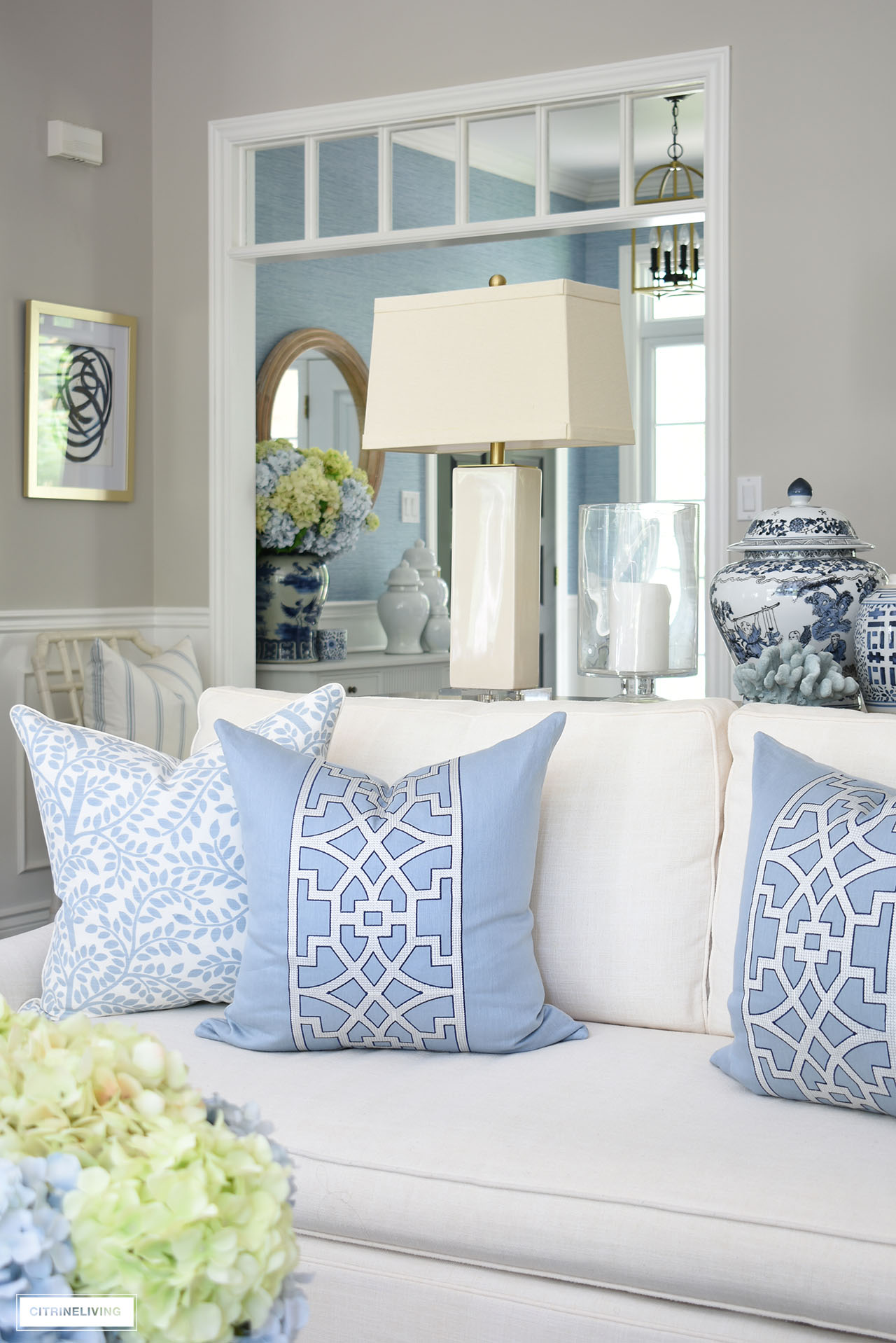 Light blue and white trellis motif designer pillow is chic on a creamy white sofa.