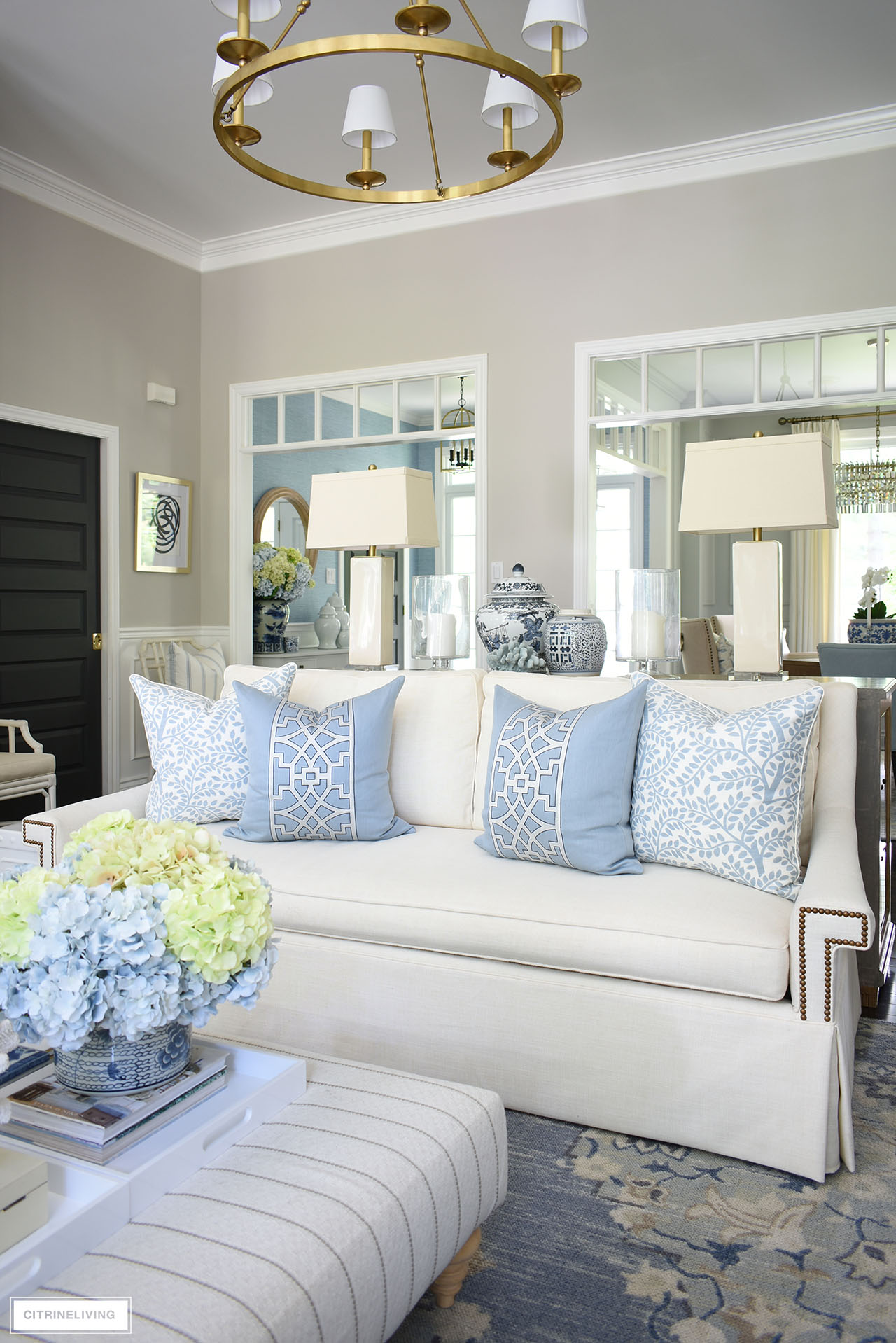 Living room with tailored white sofa decorated with soft blue and white designer pillows is chic and elegant for summer.