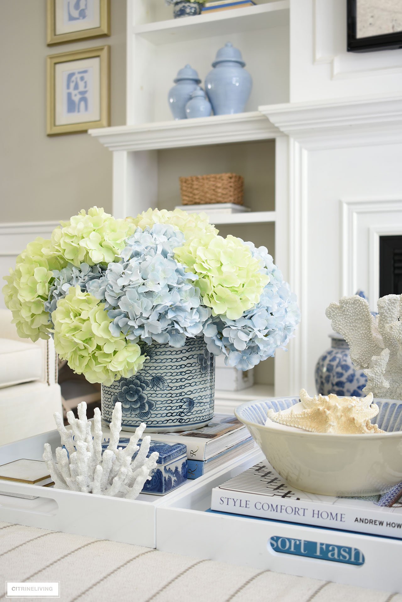 A gorgeous floral arrangement in light blue and green in a chic chinoiserie planter, styled for summer with seashells and coral.